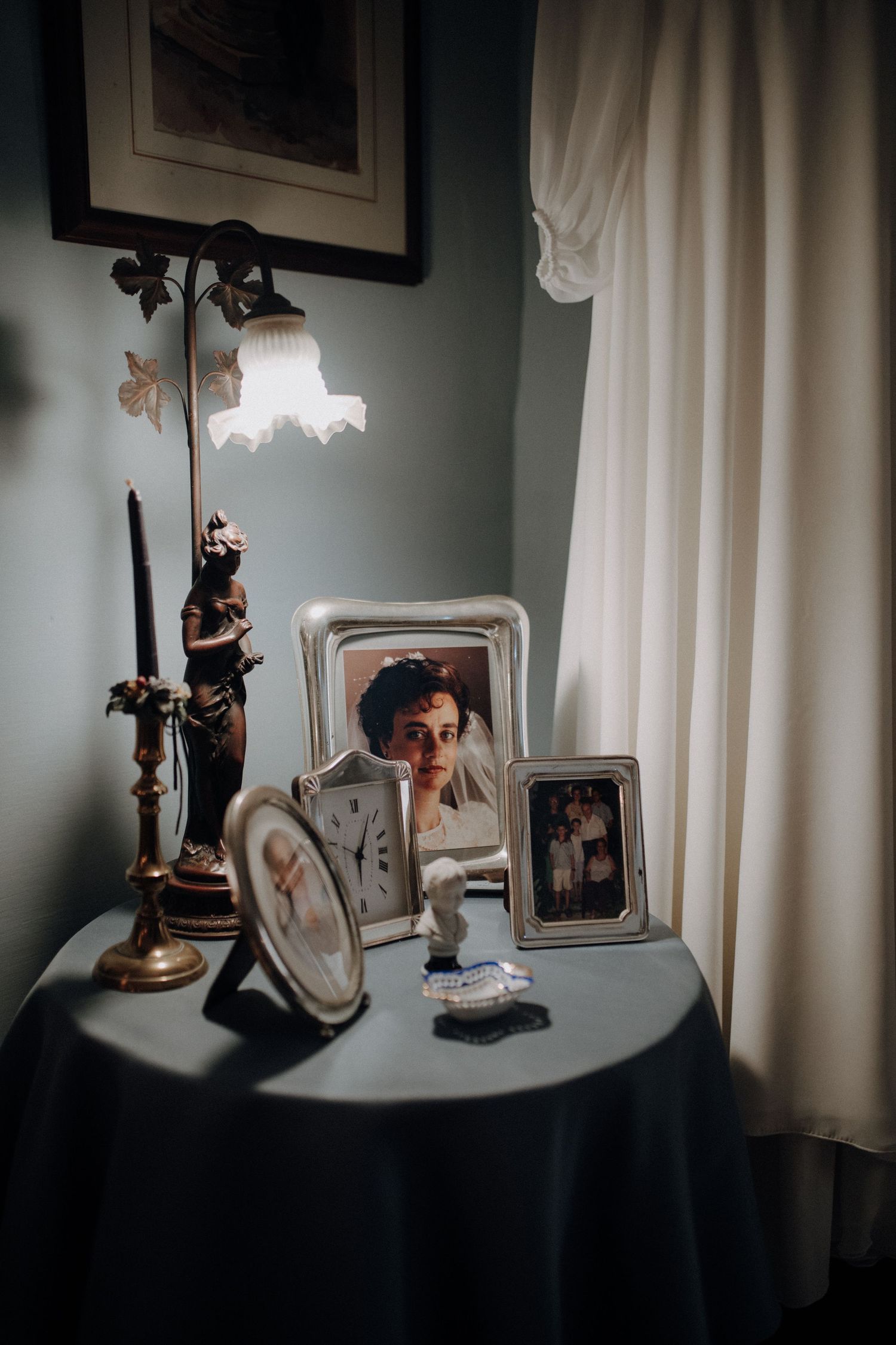 Vintage-style table setting with antique frames and lamp creating dramatic shadows.