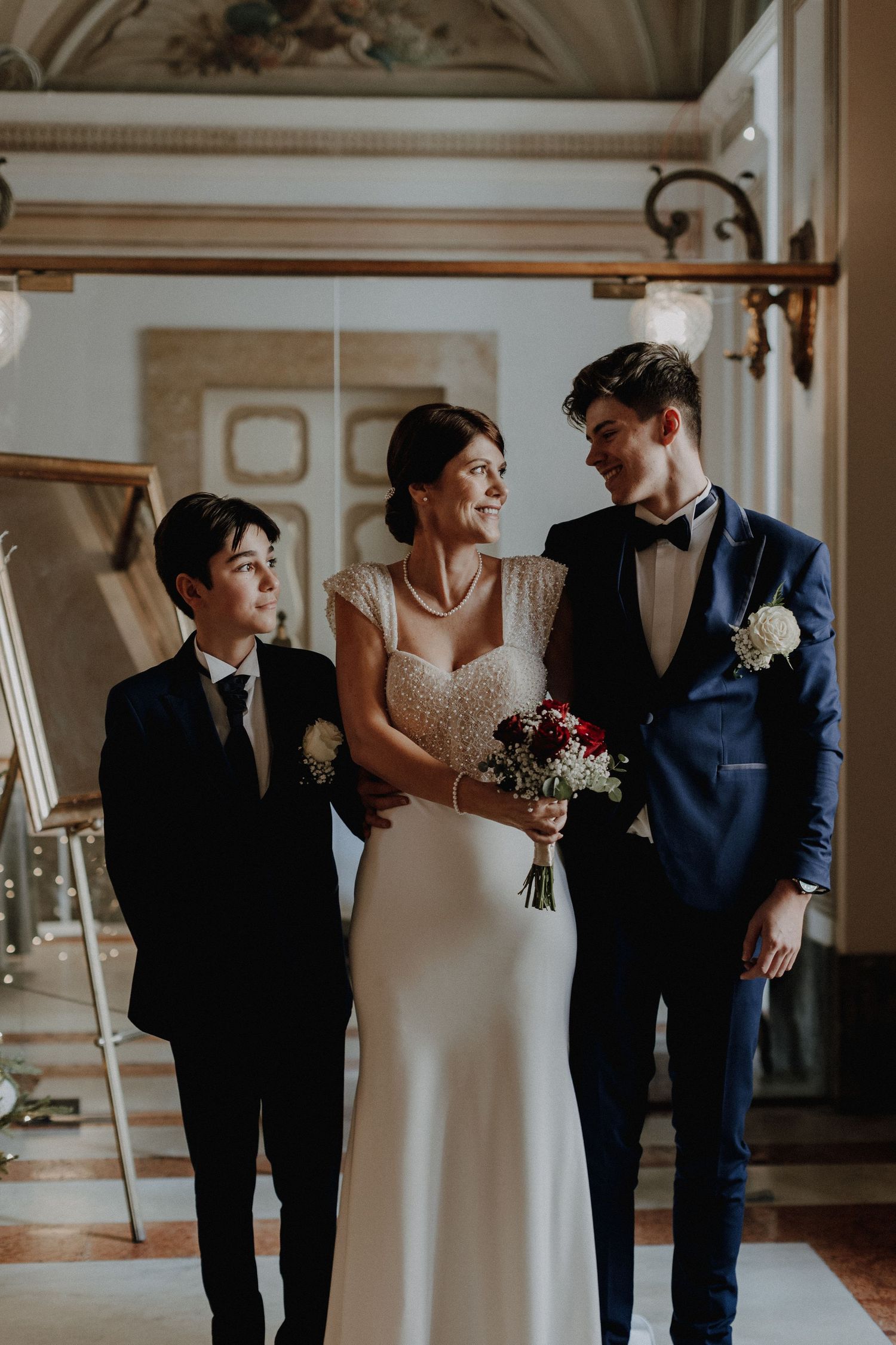 Wedding party poses together in an ornate indoor venue.