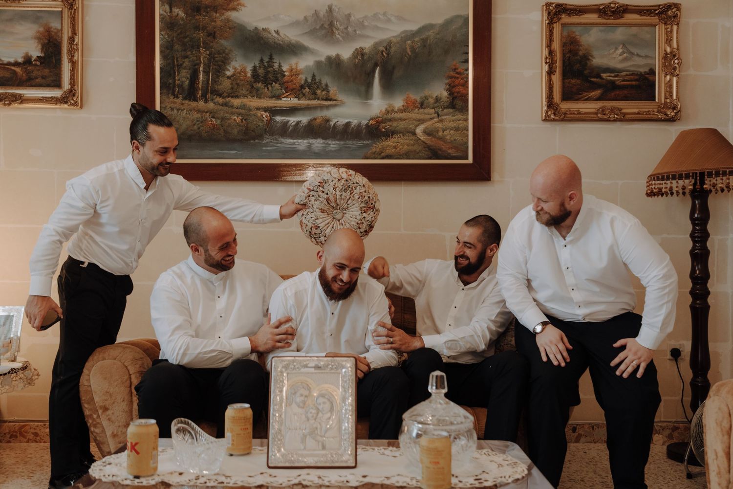 People sharing laughter while sitting on wooden bench under framed landscape paintings.