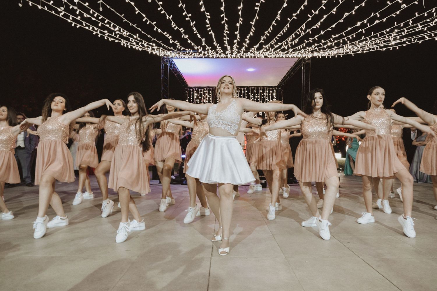 Dance performance featuring synchronized choreography under a canopy of string lights.