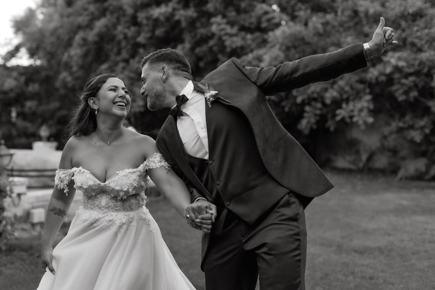 A joyful candid moment between newlyweds sharing a laugh in a garden setting.