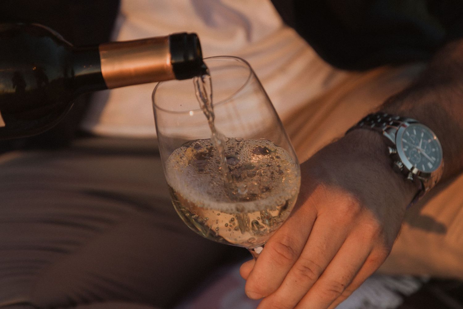 Close-up of hands holding wine glasses during an intimate outdoor moment.