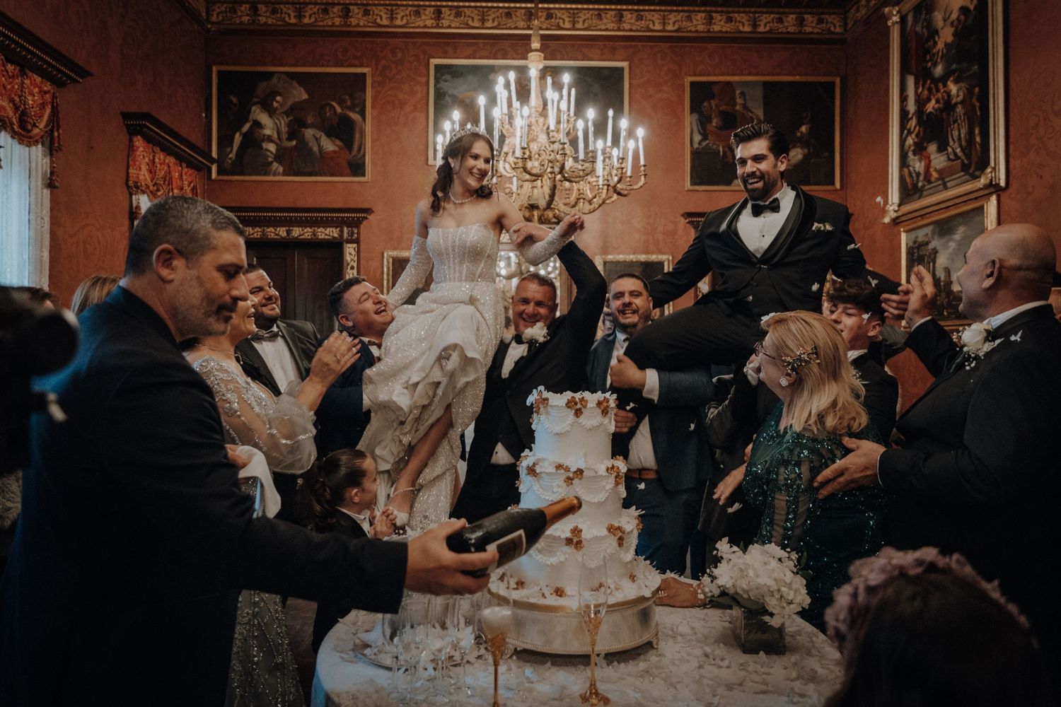 An elegant wedding celebration in a luxurious ballroom with chandelier lighting.