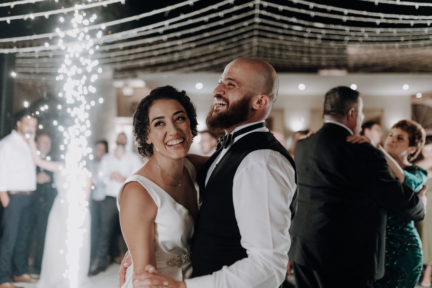 Festive moment captured during wedding reception dance with sparkler effects in background.