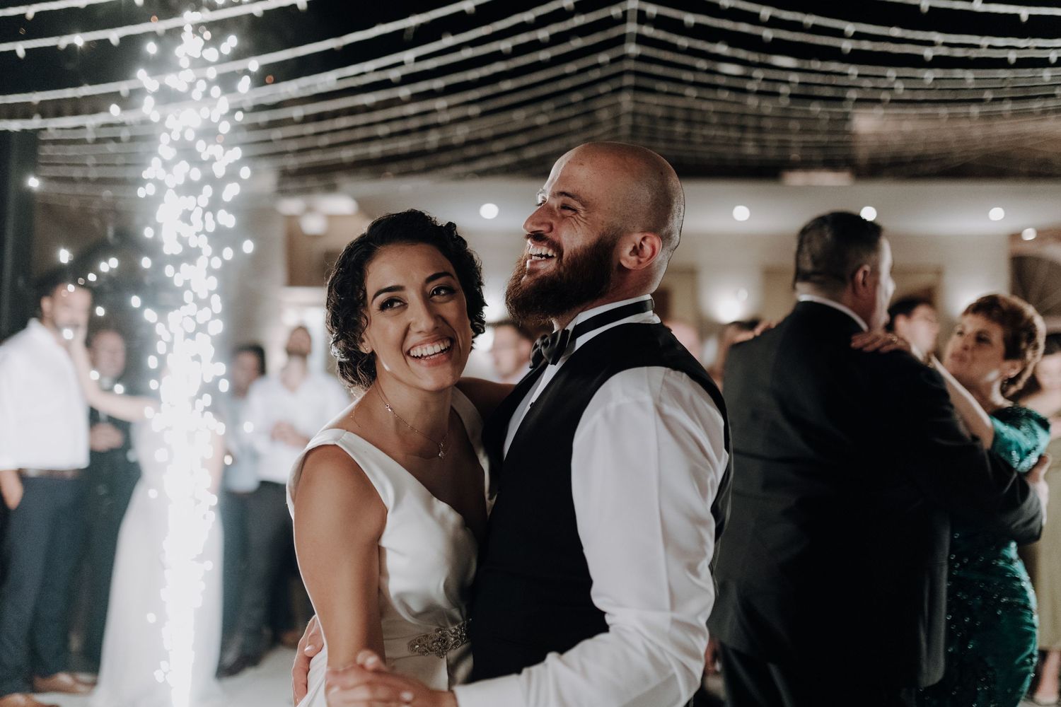 A couple dances together at their wedding reception with string lights illuminating the celebration.