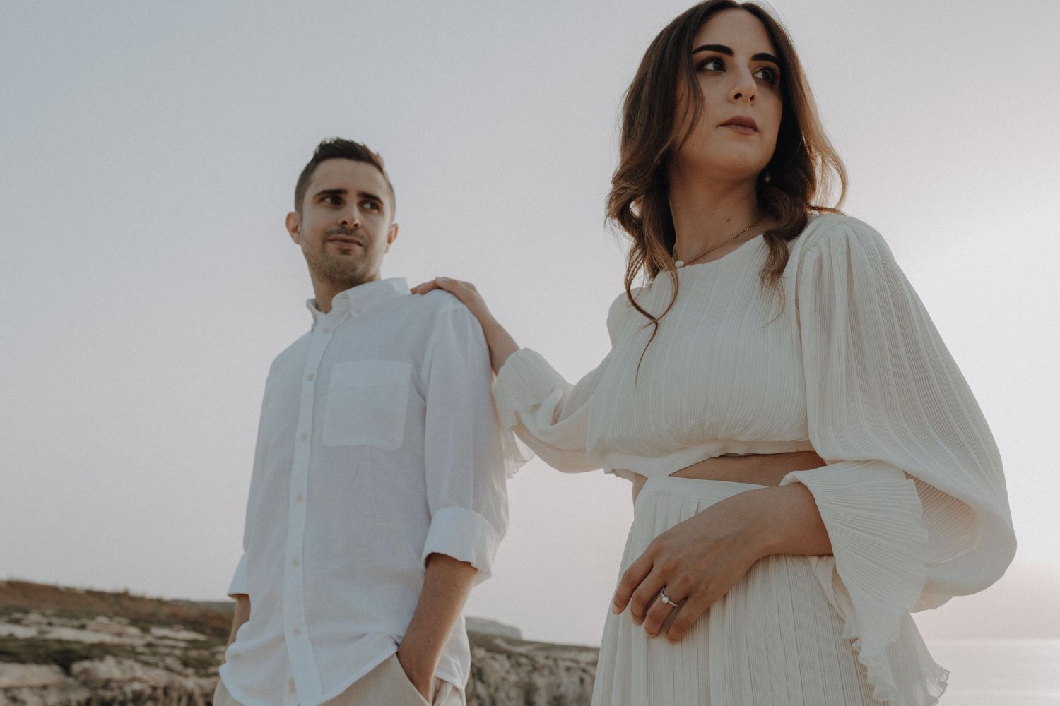 Lifestyle engagement portraits of couple in white against minimalist background.