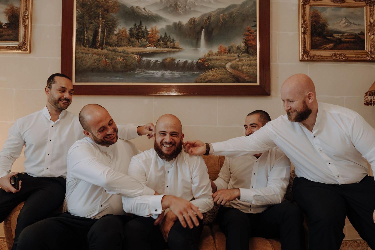 Group in white shirts seated on bench having animated conversation in elegant room.