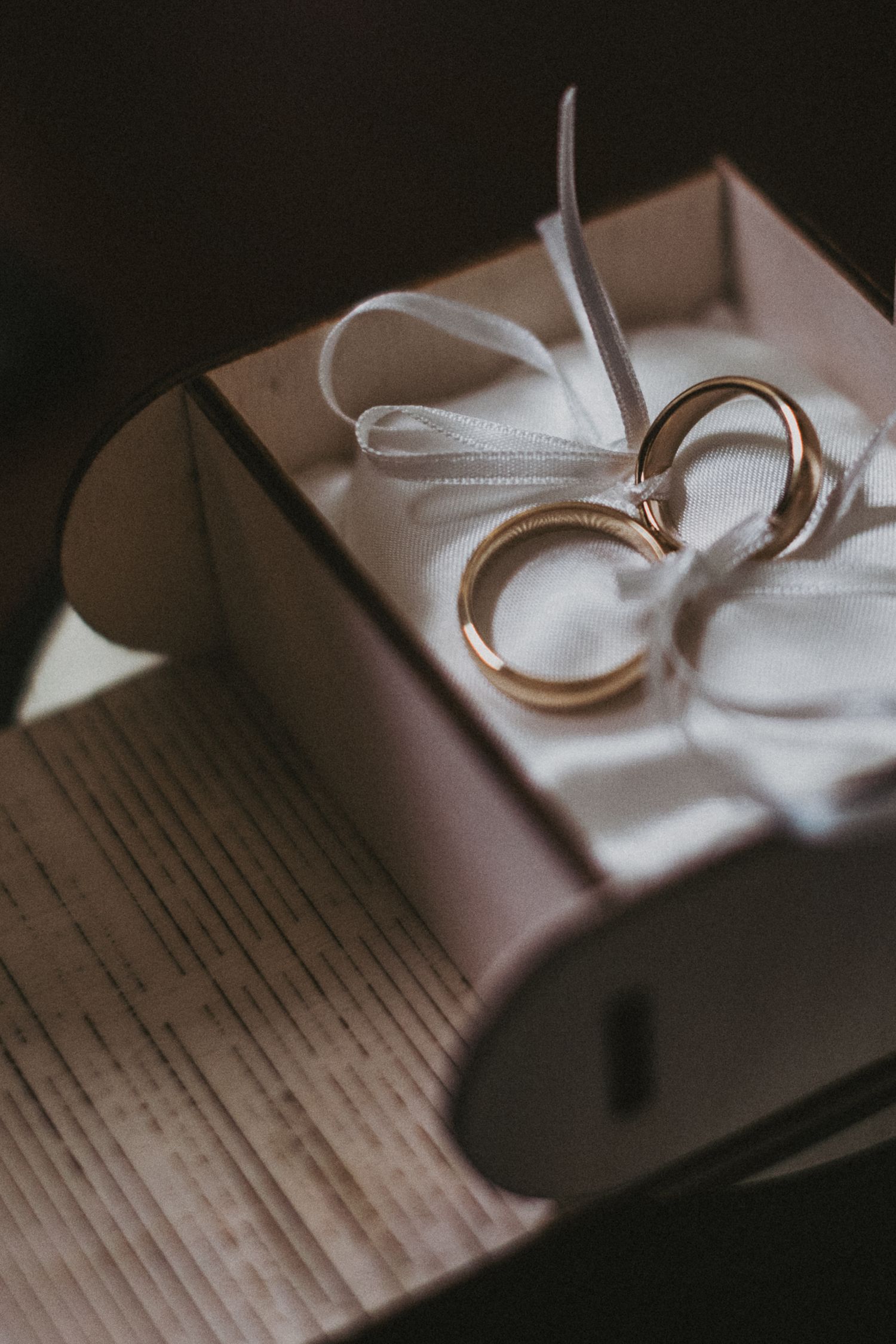 Wedding rings resting on white satin in an elegant gift box.