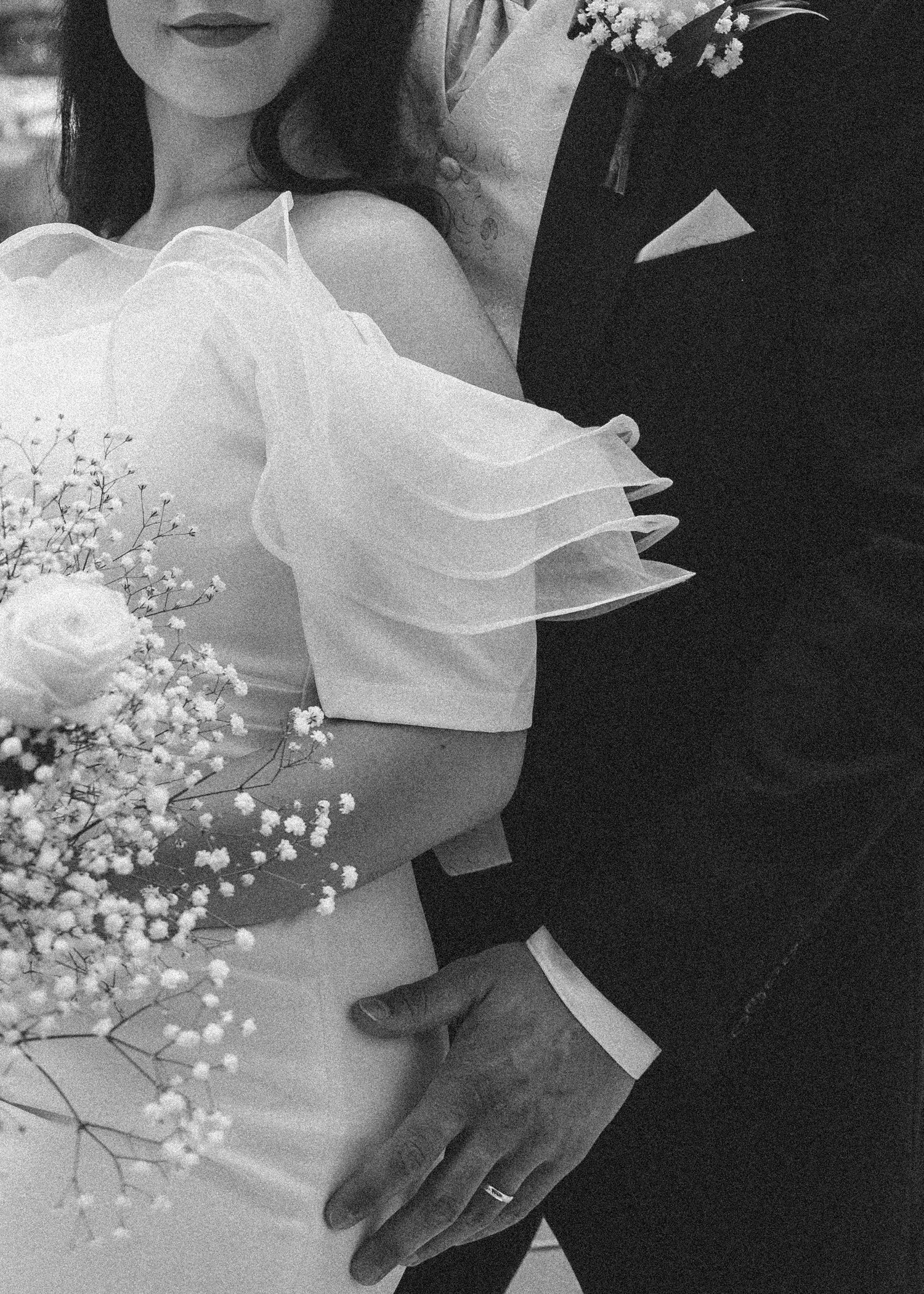Artistic black and white close-up of couple with baby's breath bouquet.