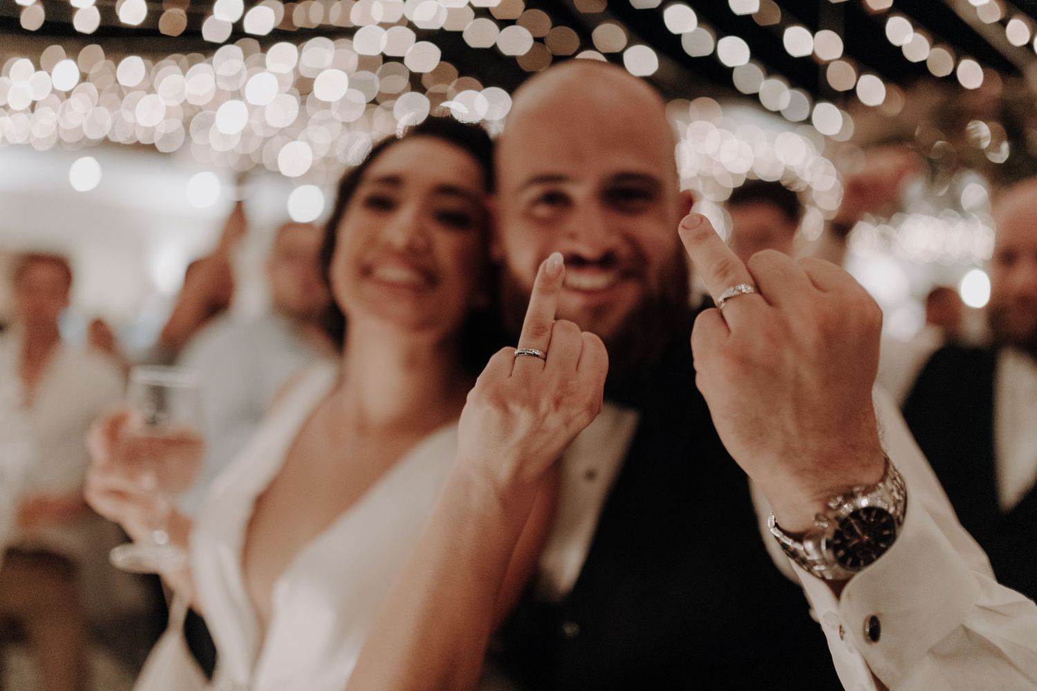Candid celebration moment under twinkling reception lights with champagne glasses.