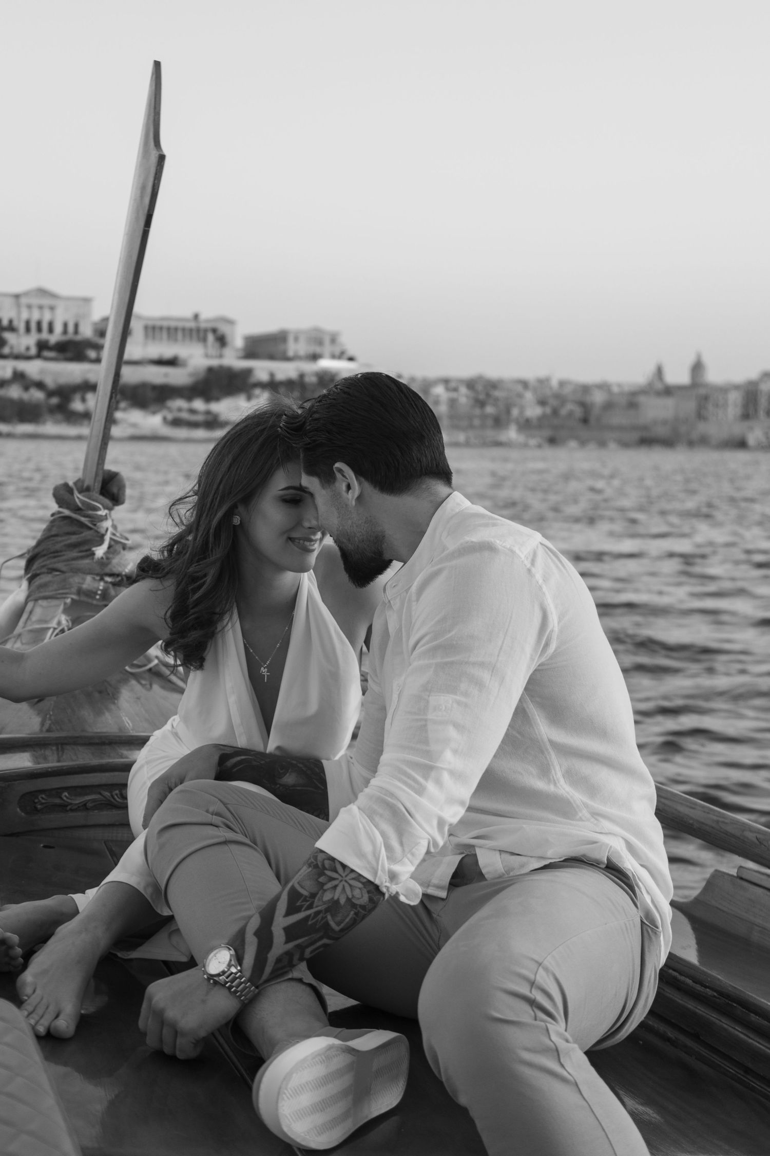 Black and white photo of a couple lounging on a boat deck with water views.