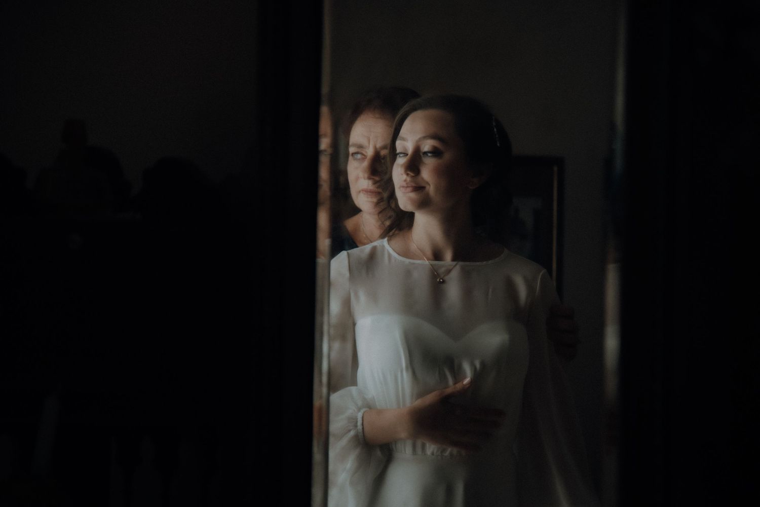 Moody portrait through window reflection showing figure in white dress.