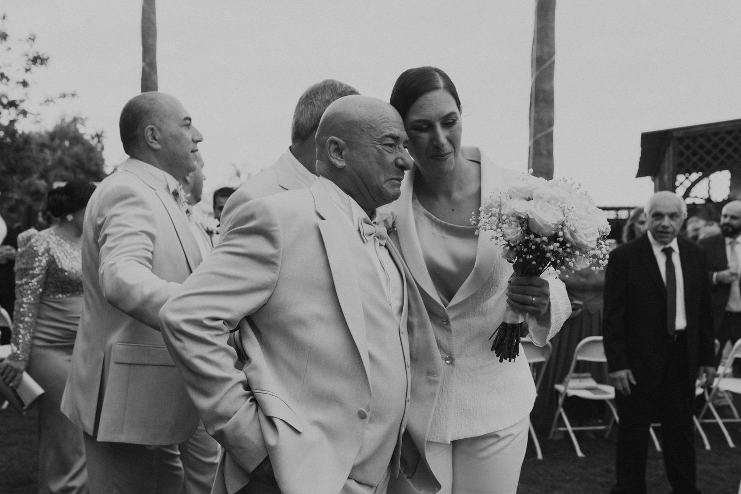 Black and white photo of people dancing at an outdoor celebration event.