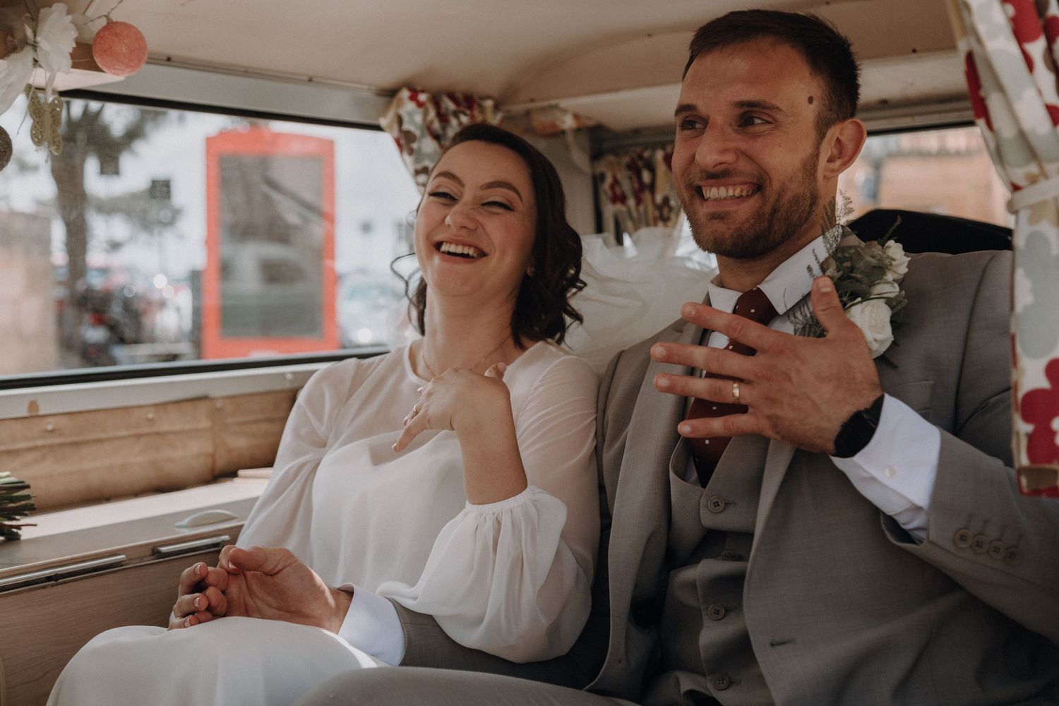 A happy couple laughs together in the back of their decorated wedding van.