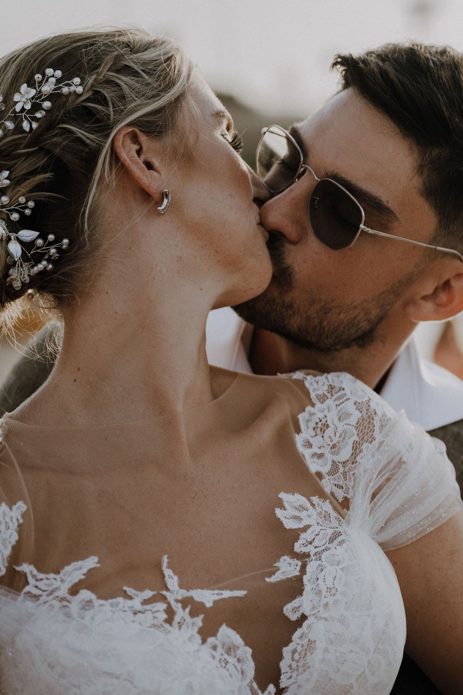 Close-up wedding photo showing intimate moment between newlyweds with lace dress detail.