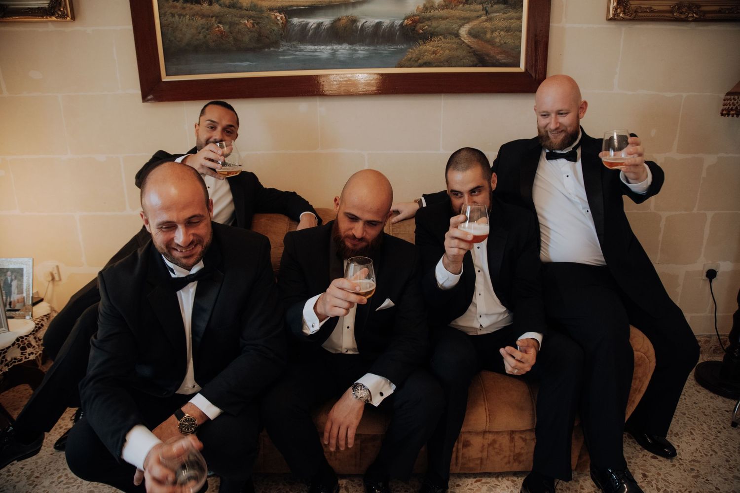 Group of men in black suits having celebratory drinks together in an elegant indoor setting.
