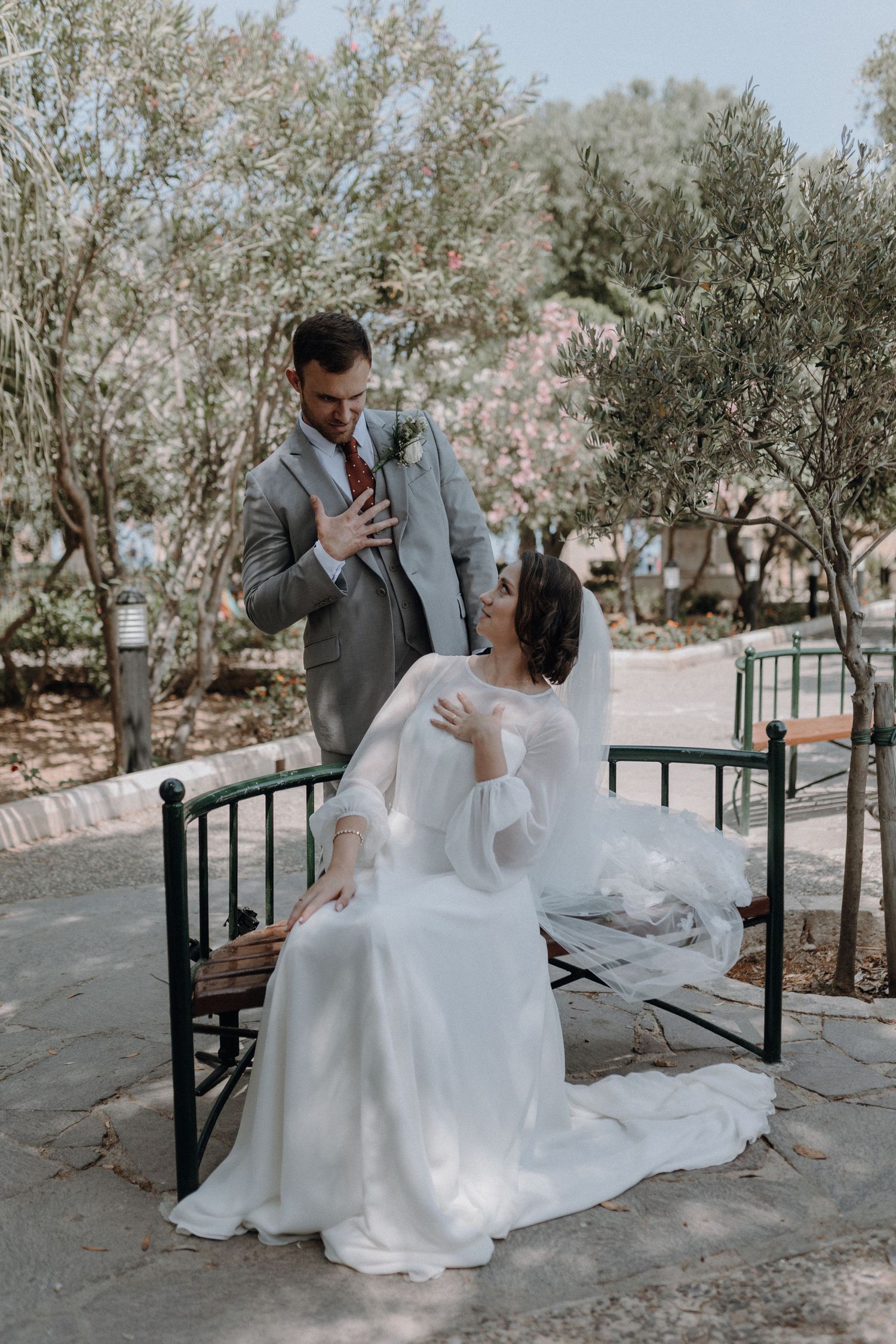 Playful wedding couple interacting on garden bench.