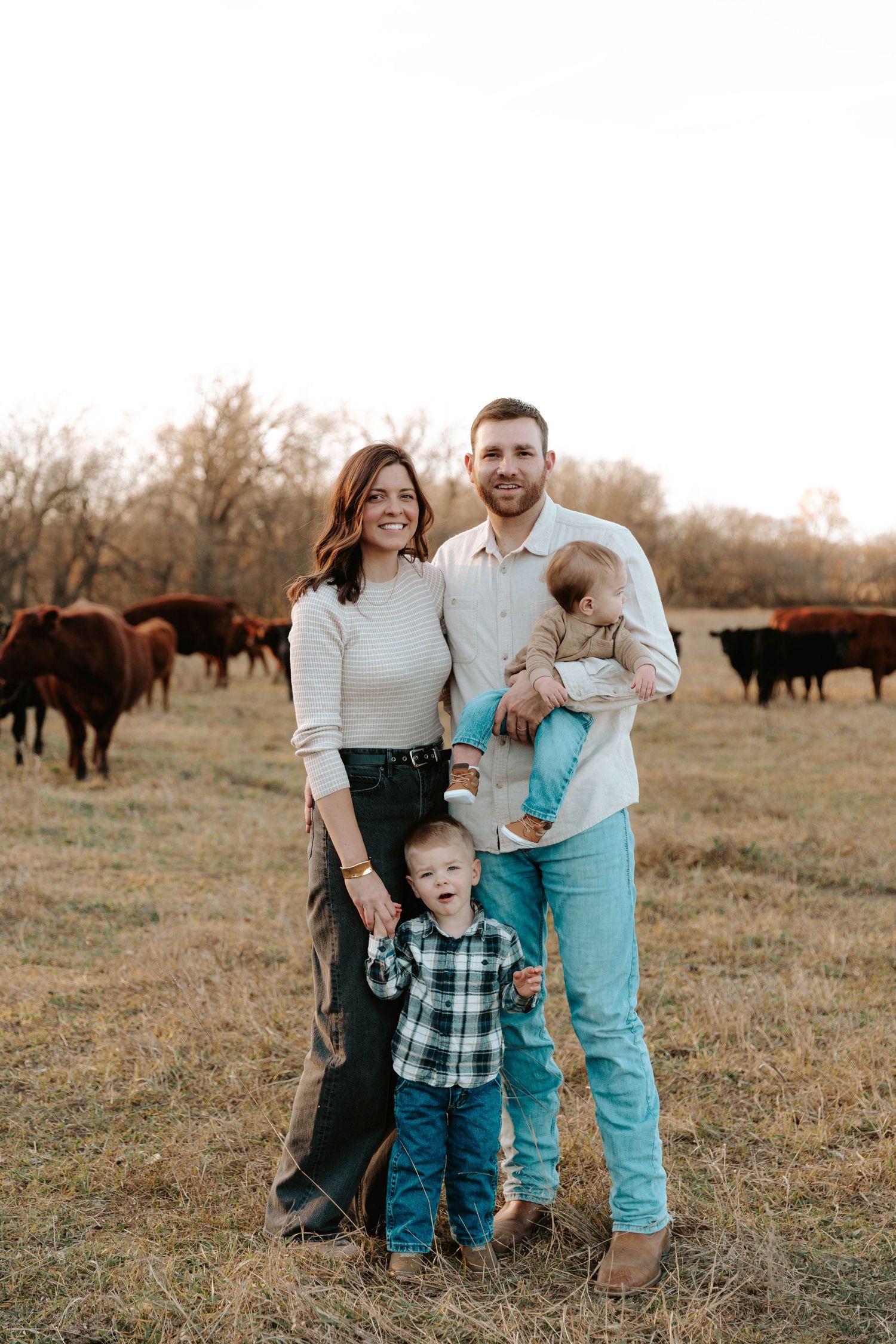 Family posing together in front of their cattle