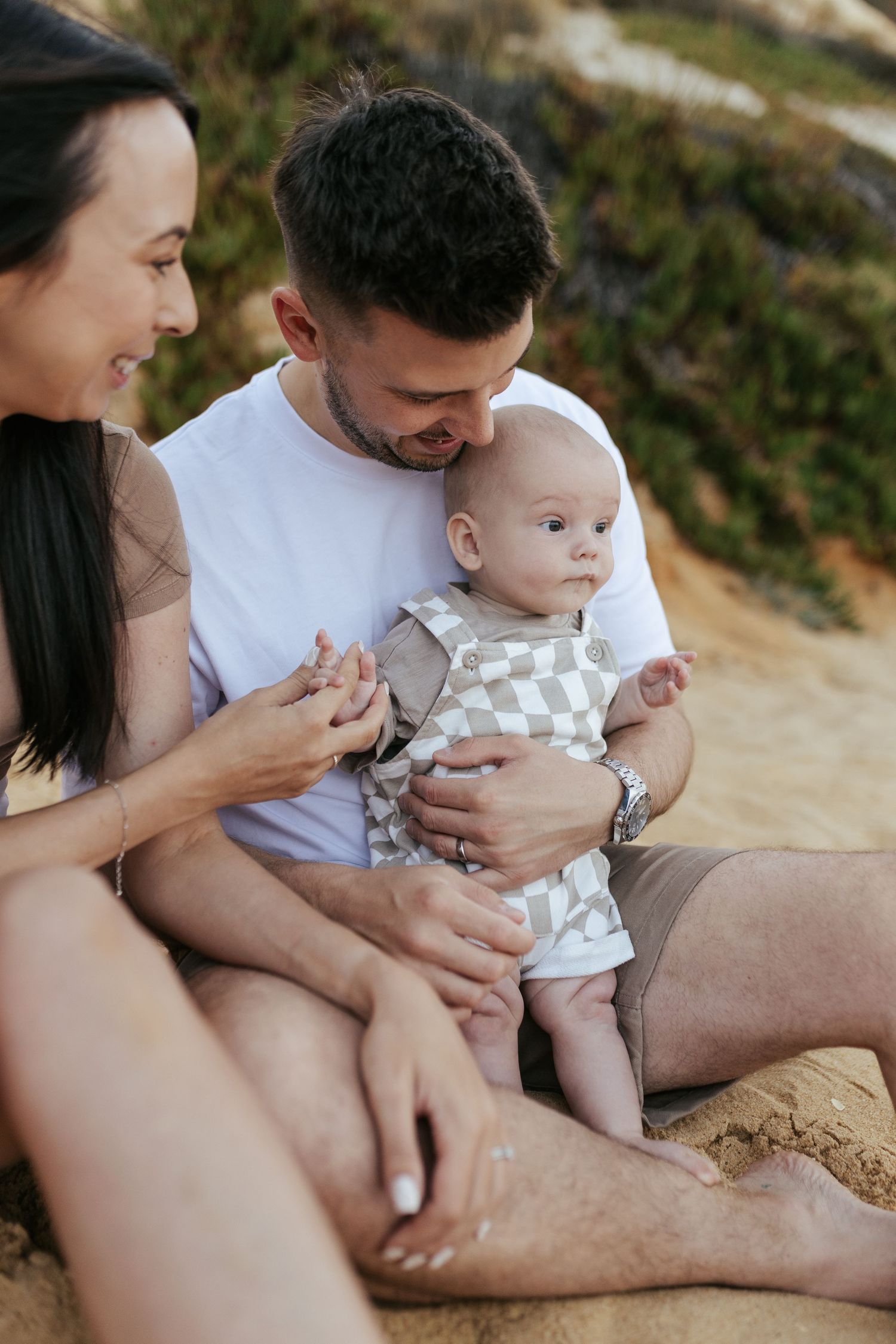 Happy family spending time together with their baby at the beach during sunset.