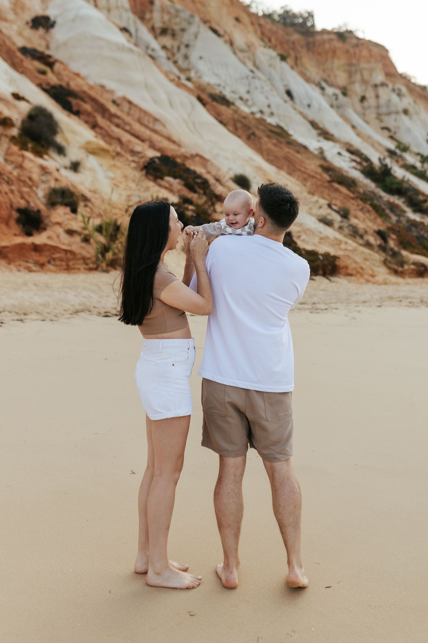 Family enjoying a beach day together with cliffs in the background at a scenic coastal location.