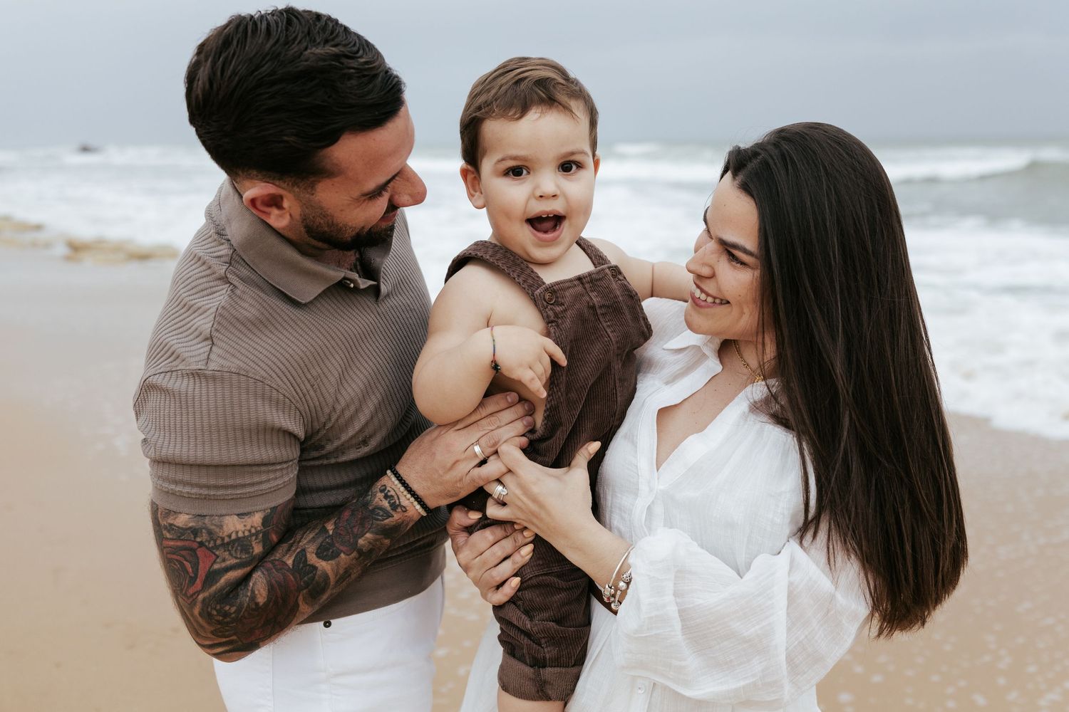 A happy group spending time together on a sandy beach with ocean waves in the background.