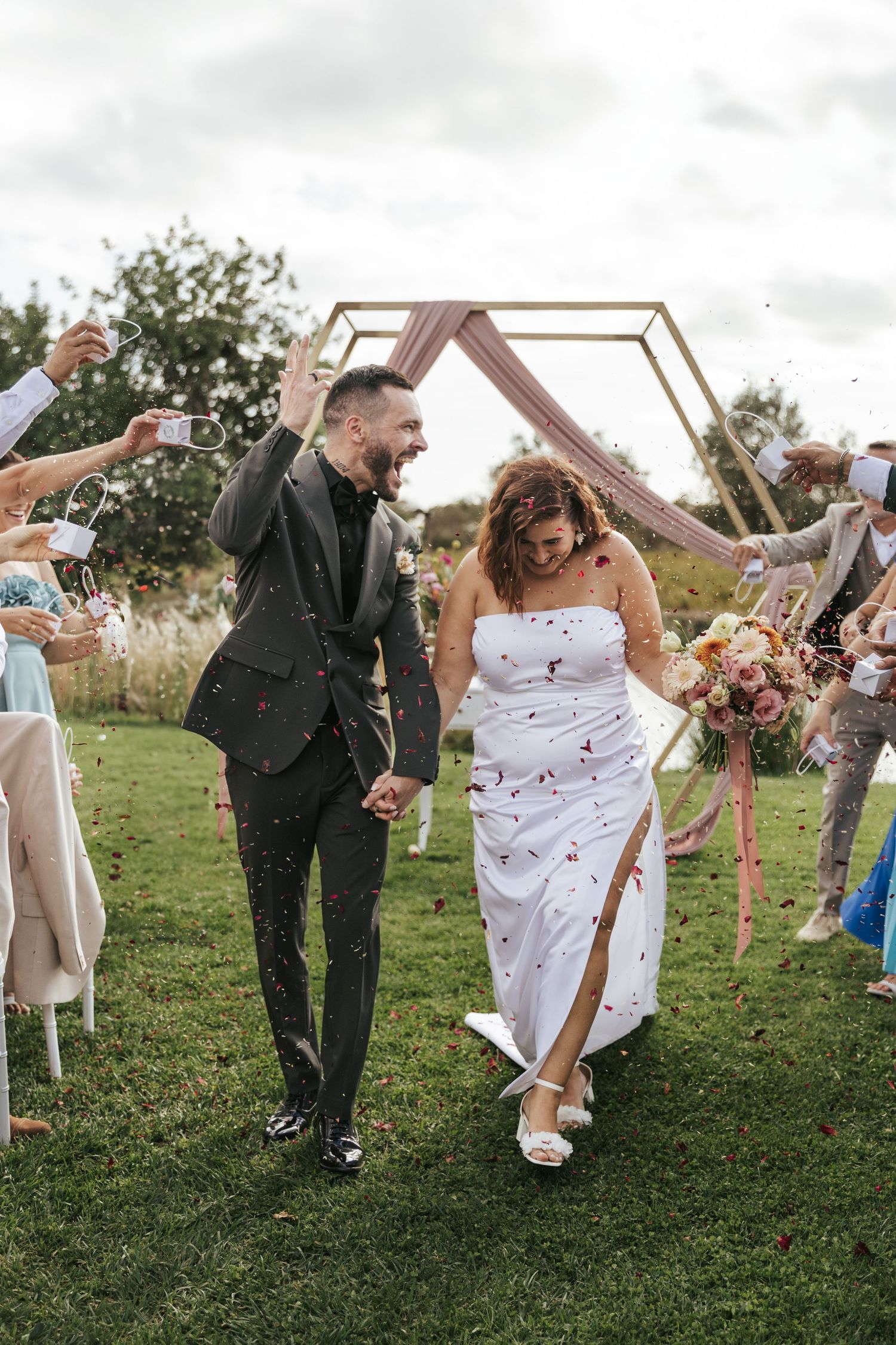 A couple dances playfully on a grassy lawn during their wedding celebration, creating a series of candid moments.