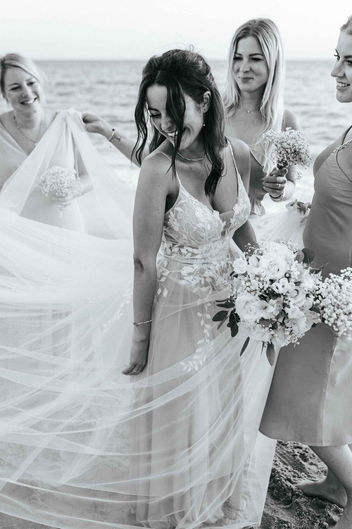 Wedding party in flowing white and pastel dresses walking together with floral bouquets.