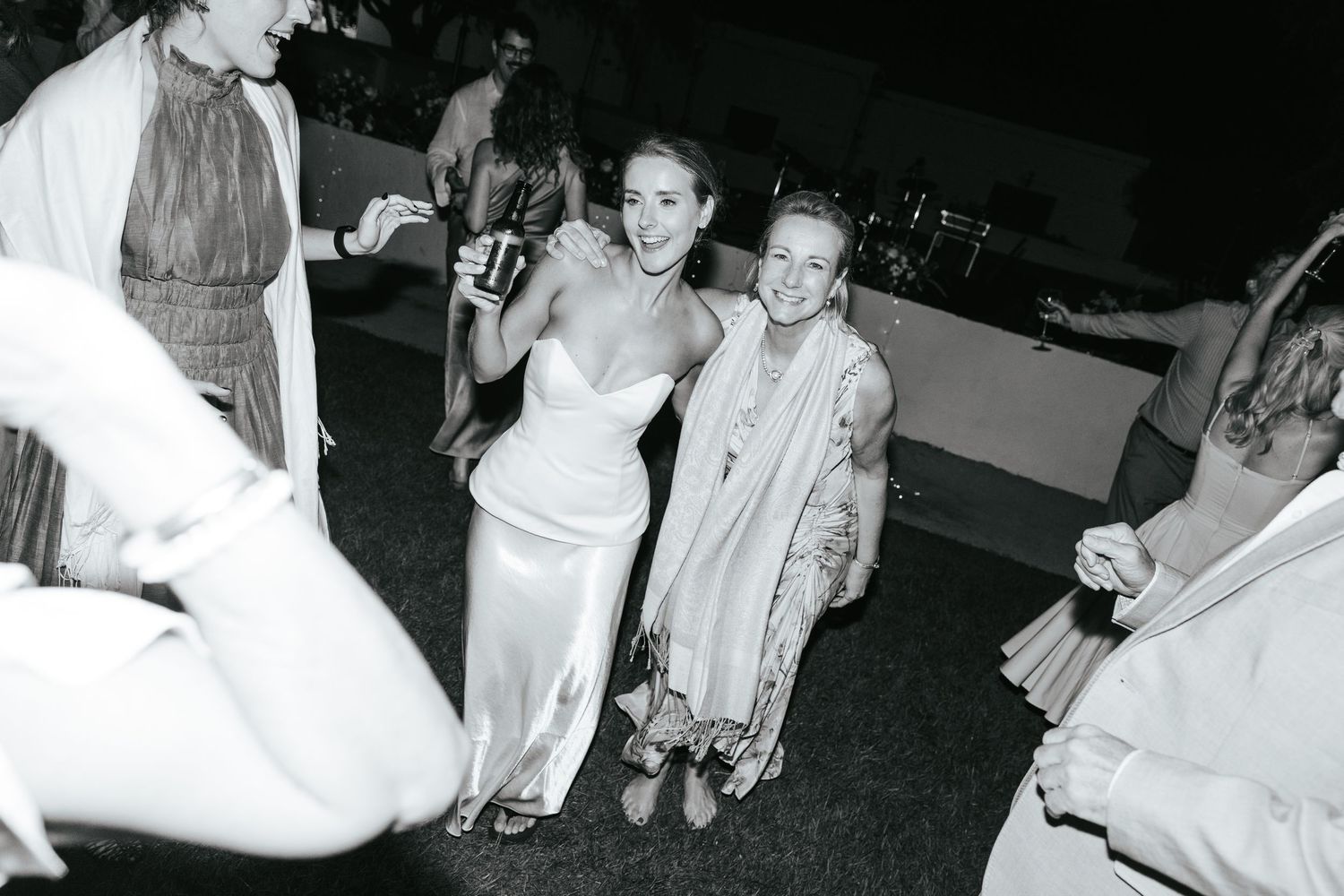 Guests smile and socialize at an outdoor wedding reception in black and white photo.