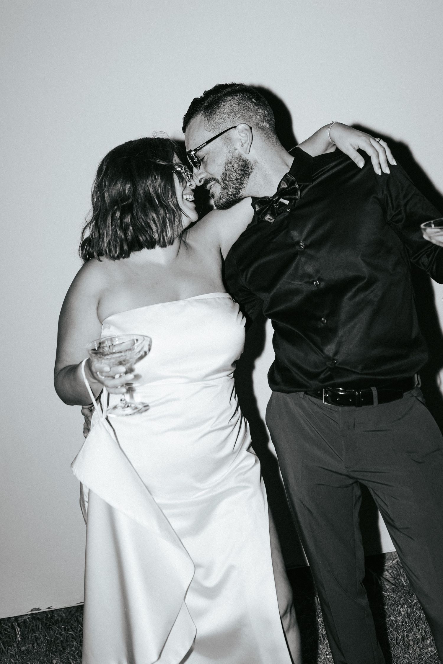 Black and white photo of a romantic wedding moment showing a couple dancing with champagne.