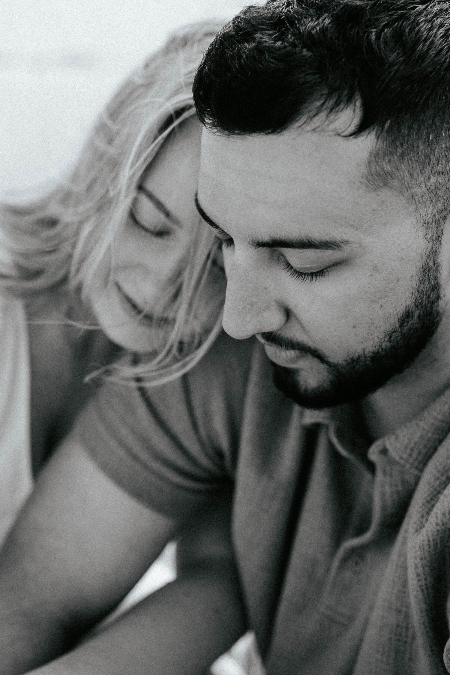 Close up black and white intimate portrait of a couple in a tender moment with soft focus and natural lighting.