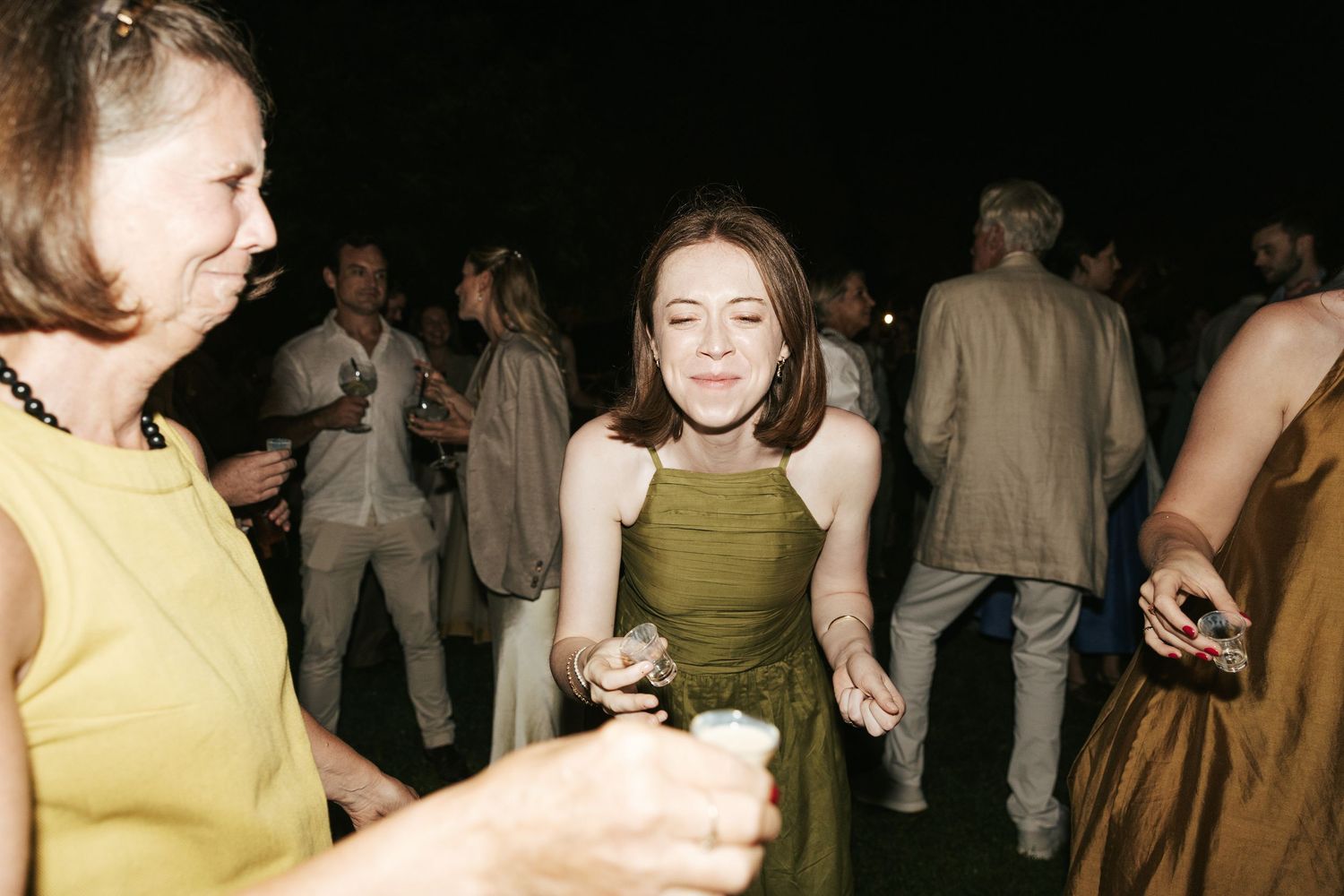 Woman in green dress dancing and smiling at an outdoor evening party event.