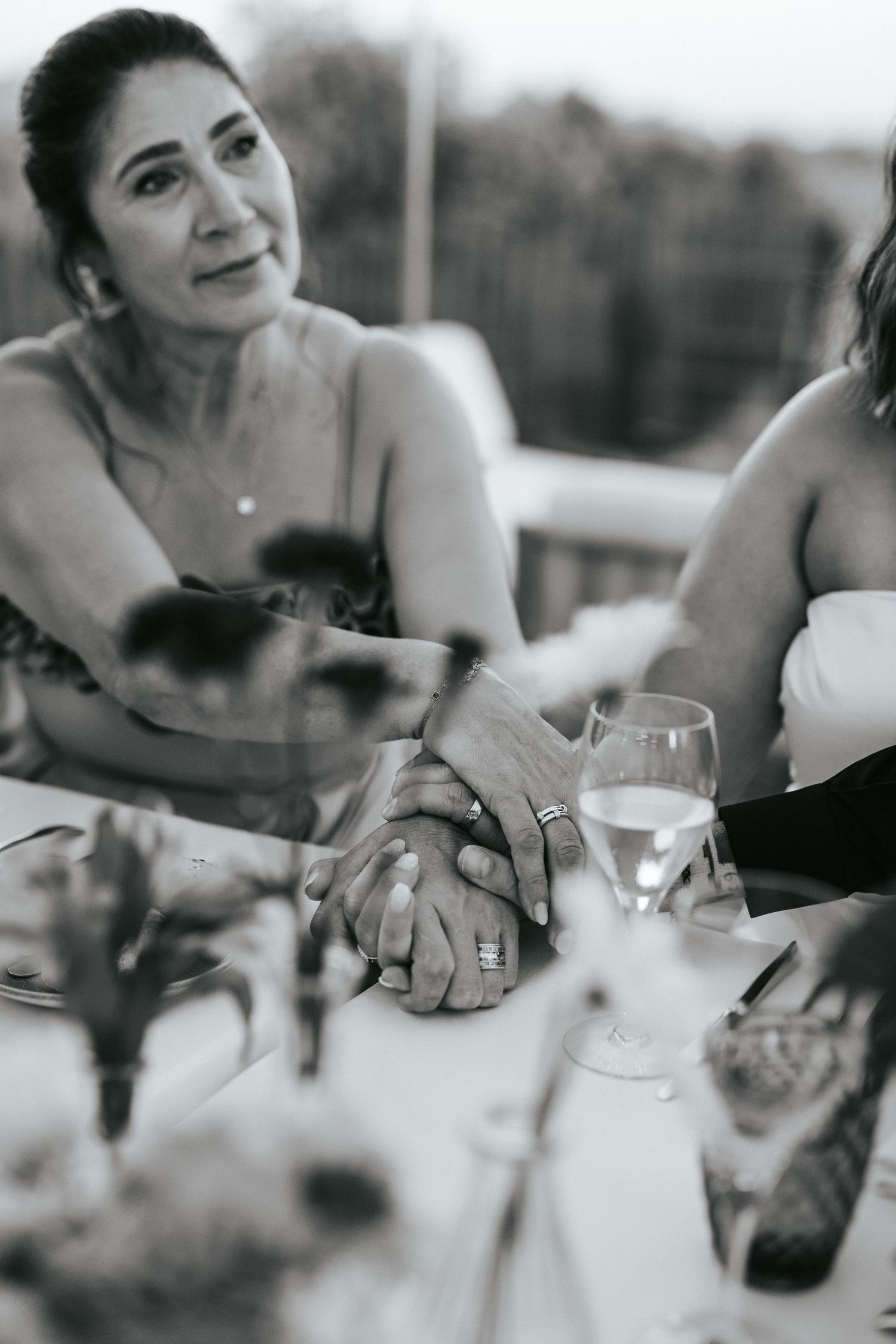 Black and white candid photo of wedding guests sharing an intimate moment at reception table.