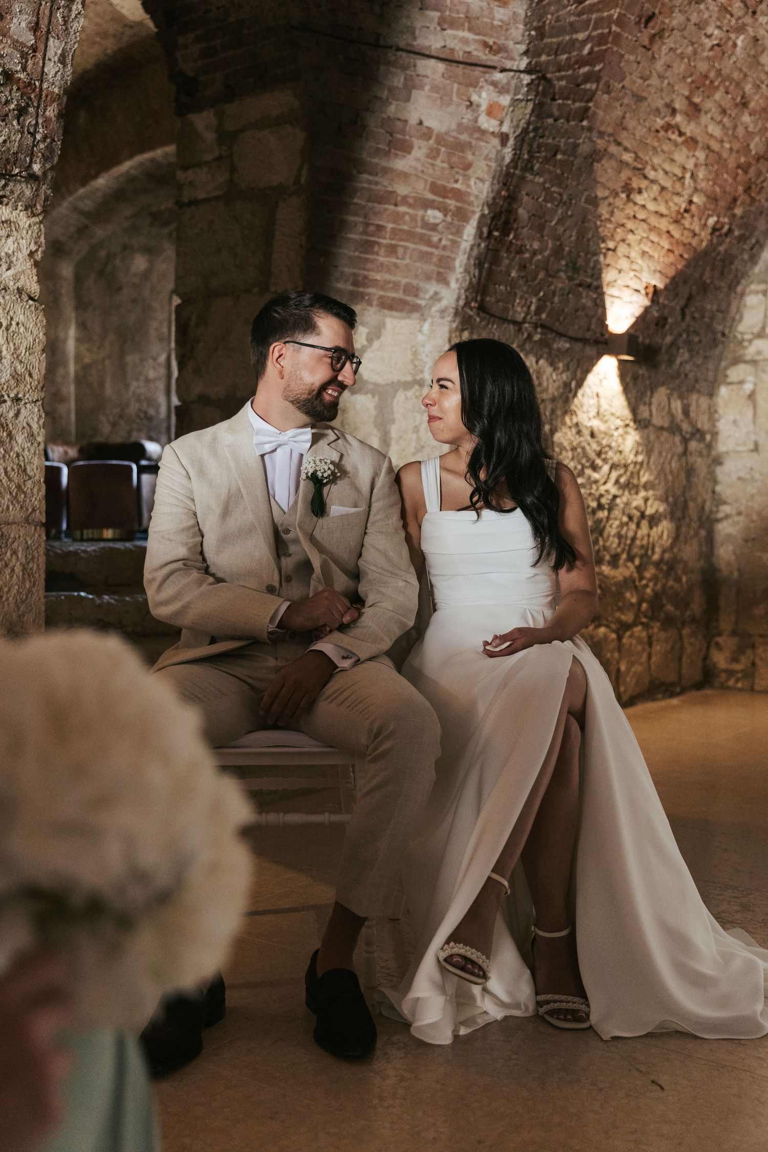 Couple shares an intimate moment in a rustic brick-walled venue during their wedding celebration.