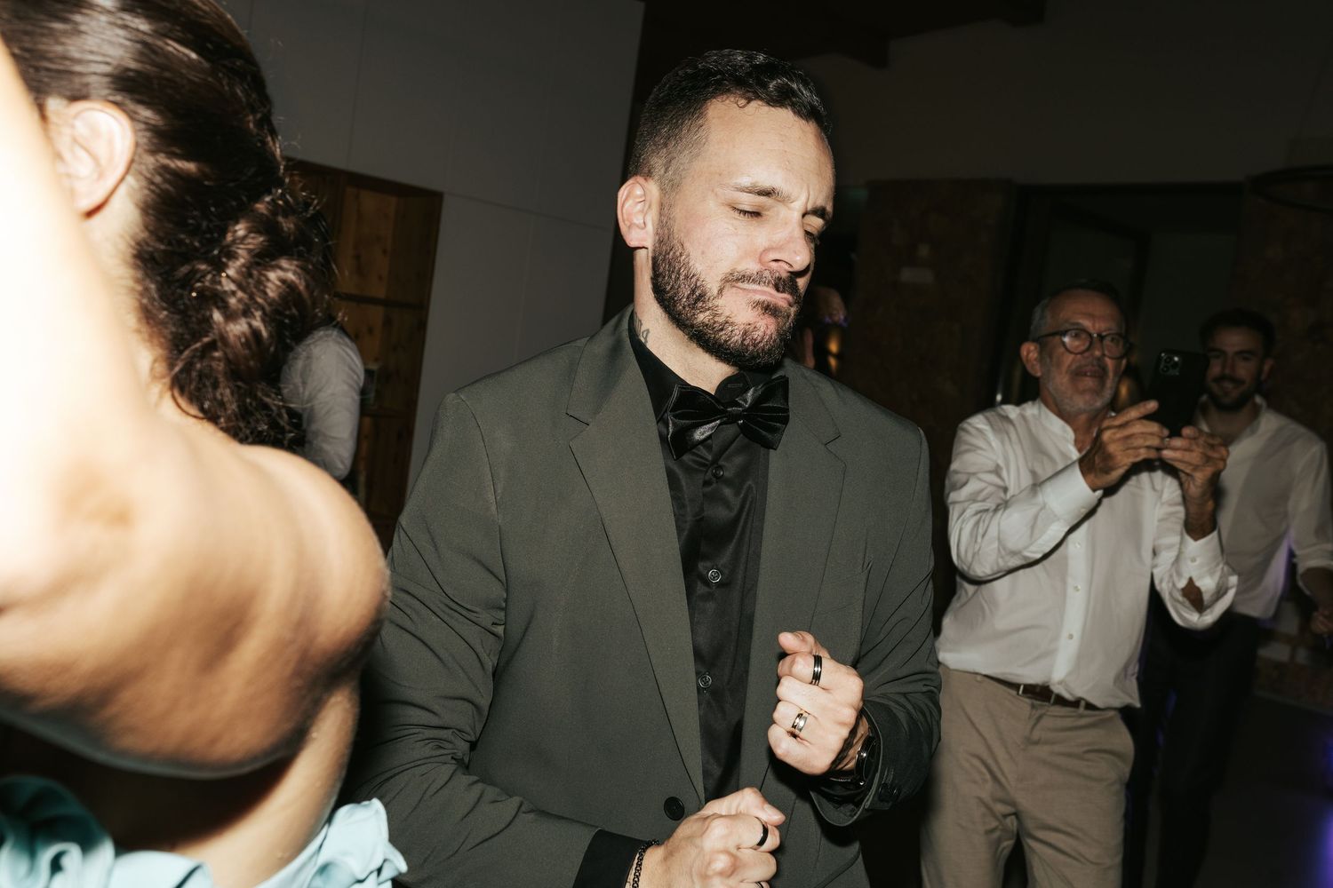 Wedding guests dancing and celebrating at an indoor reception venue.