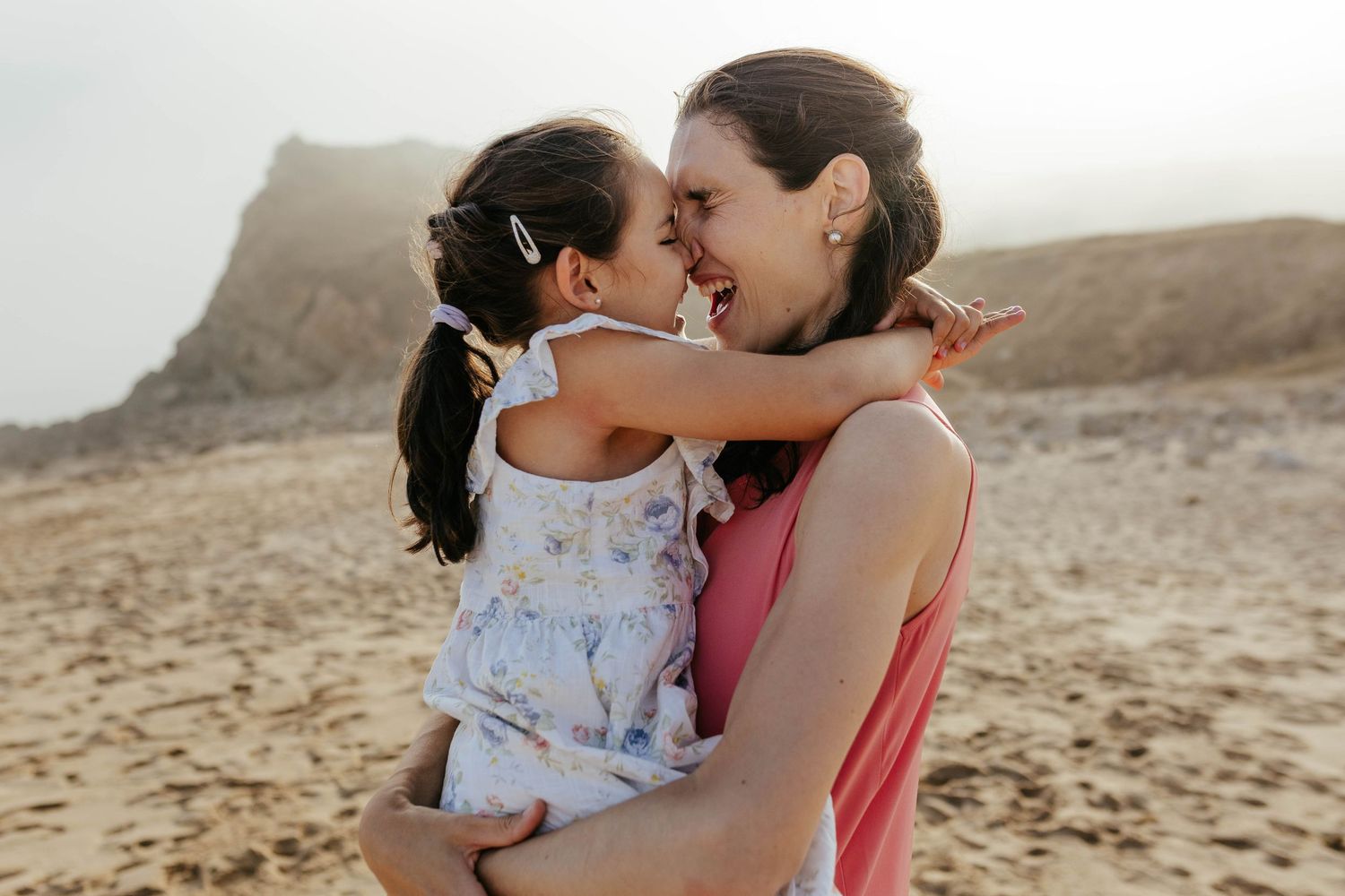 A tender moment between parent and child sharing a laugh together in a desert landscape during golden hour.