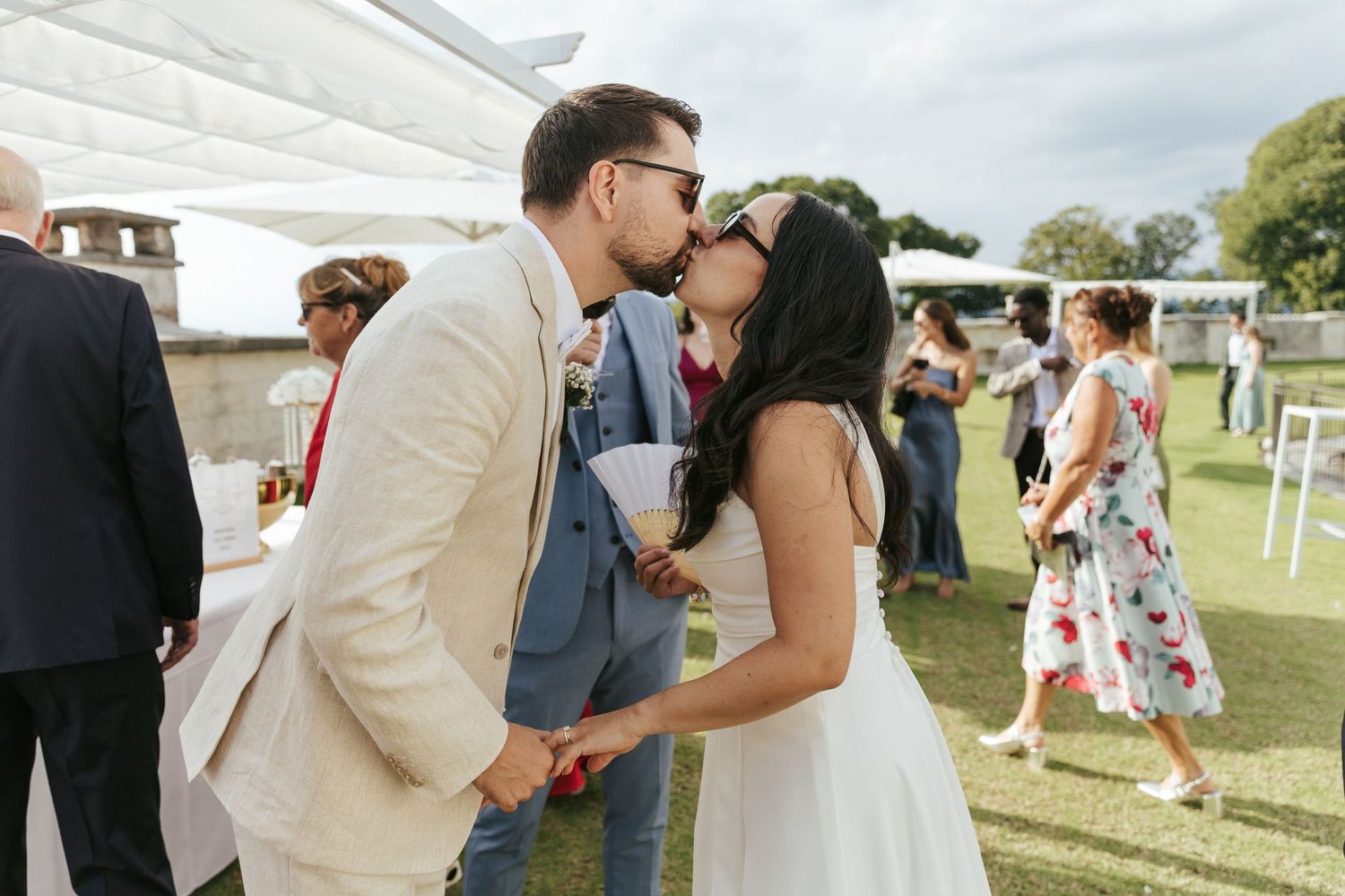 Wedding guests celebrate and dance together at an outdoor reception venue on a sunny day.