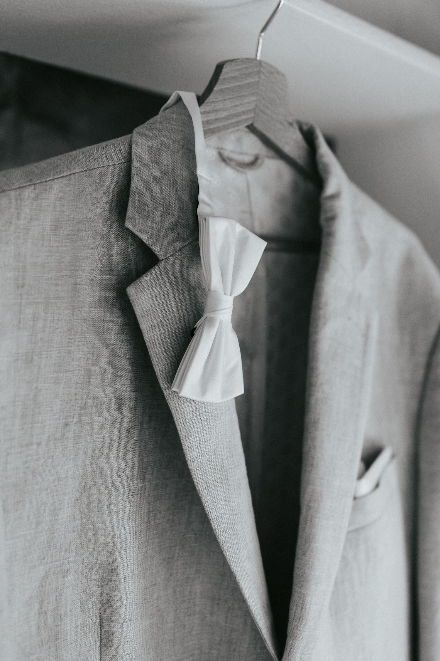 Row of light gray suits hanging neatly on hangers with crisp white dress shirts.