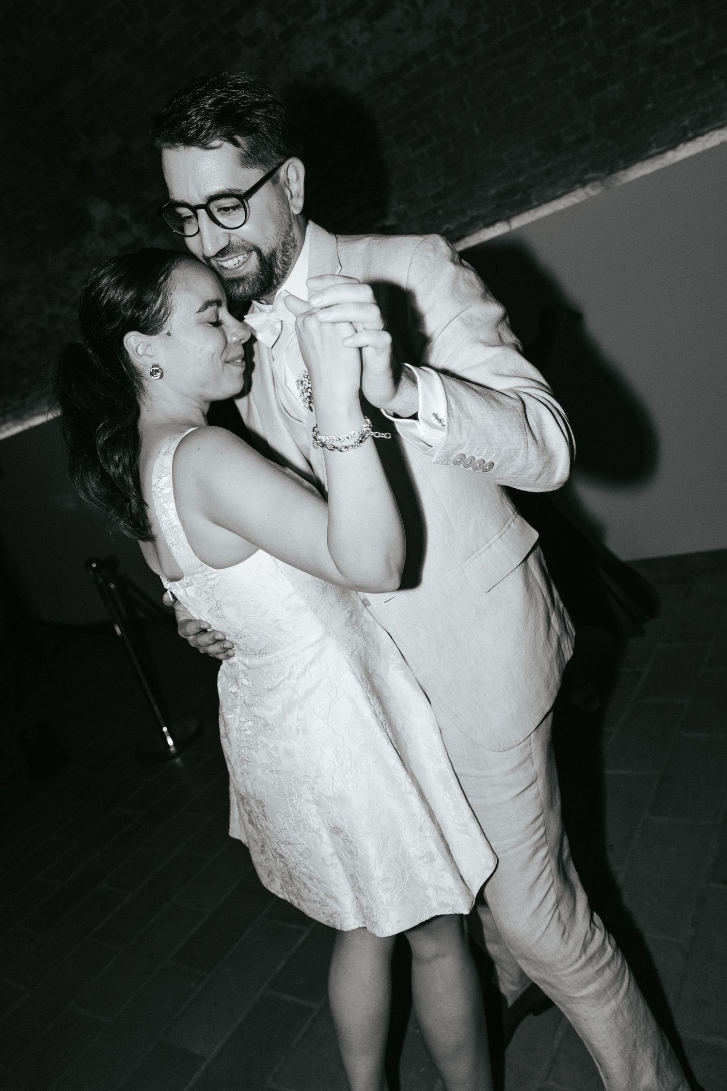 Couples dancing intimately on a dark dance floor at a wedding reception.
