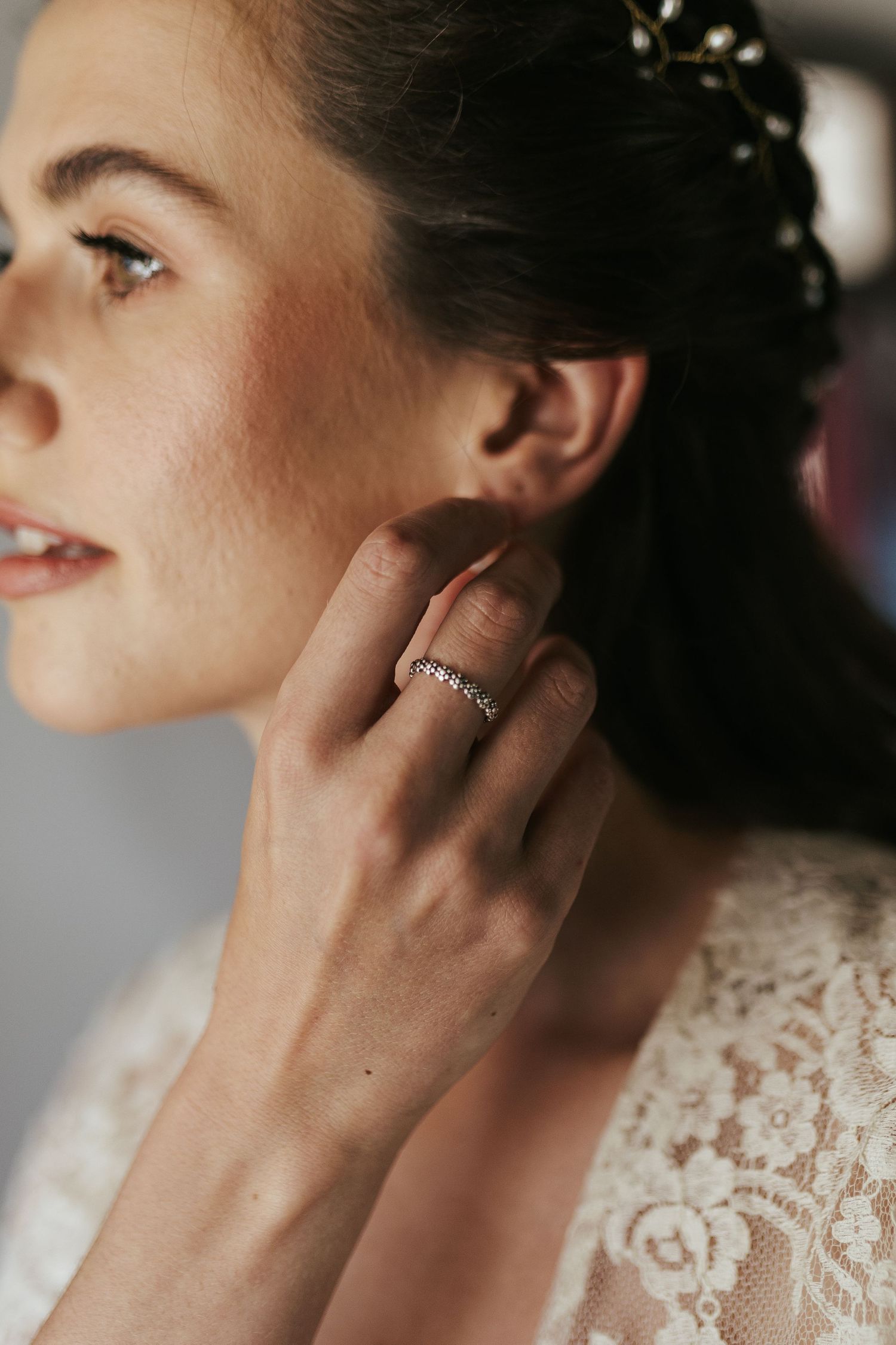 Side profile view showing delicate lace details and a sparkly ring during bridal preparation.