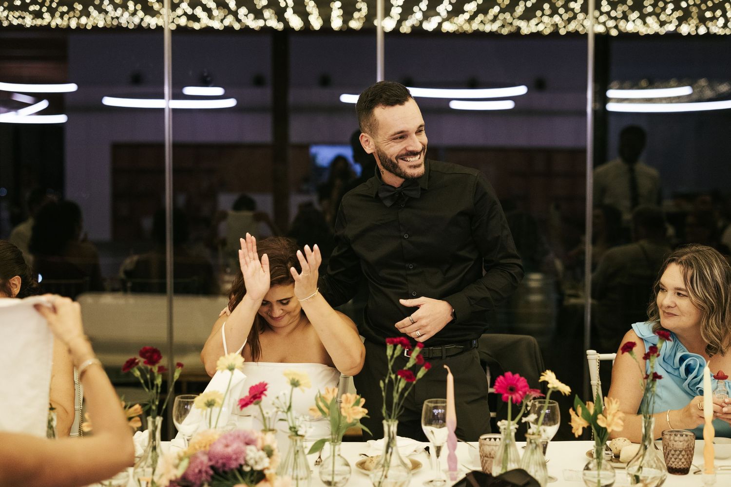 Candid laughter shared around an evening dinner table with floral centerpieces and ambient lighting.