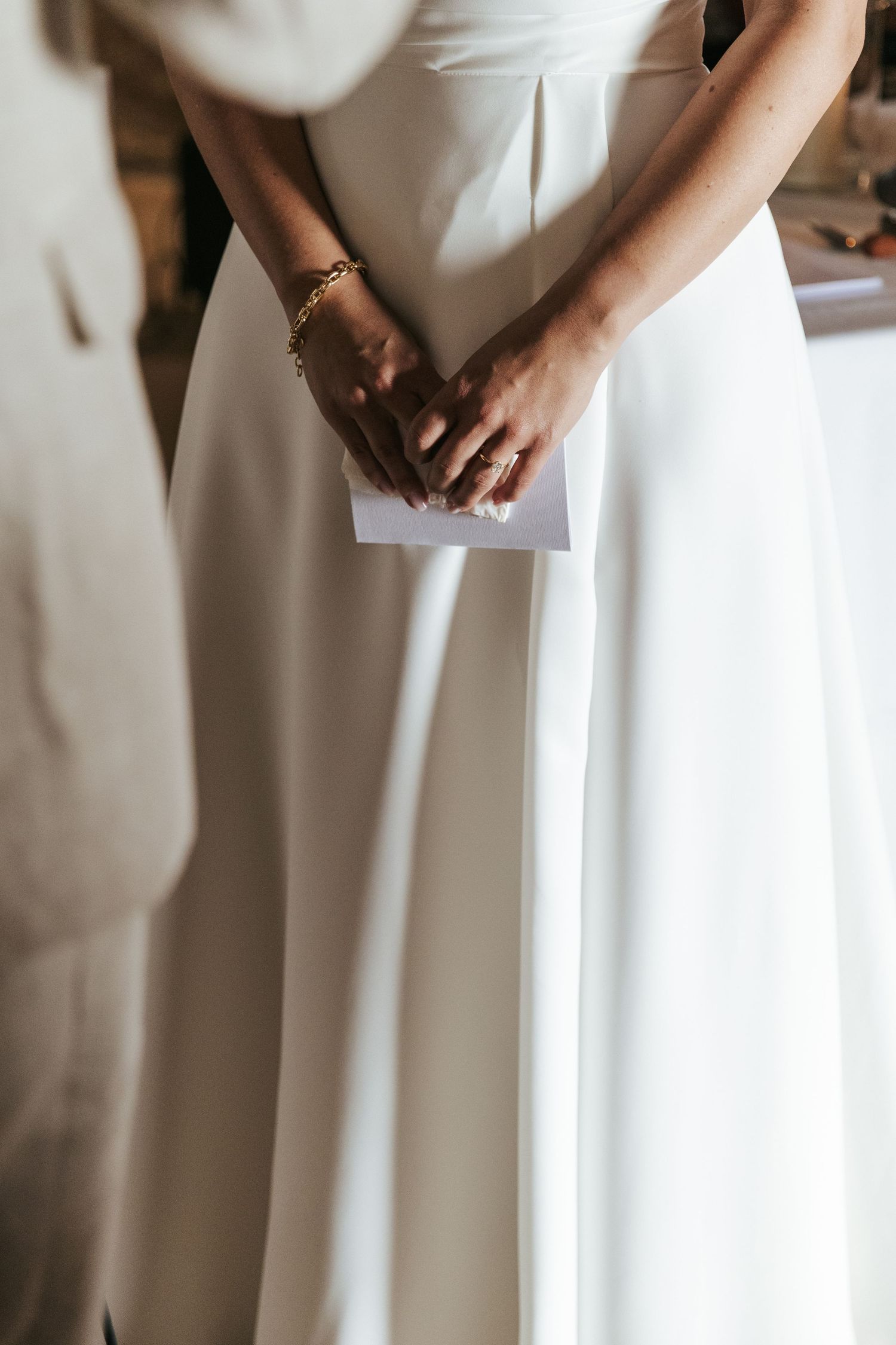 Detail shot of white wedding dress fabric and hands during ceremony.