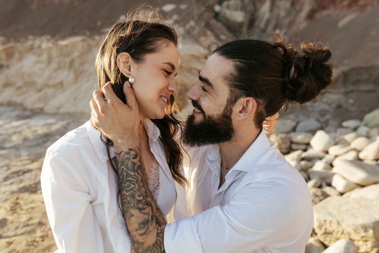 Intimate close-up of couple sharing tender moment against beach cliff backdrop. Praia da Luz, Lagos, Algarve, Portugal.
