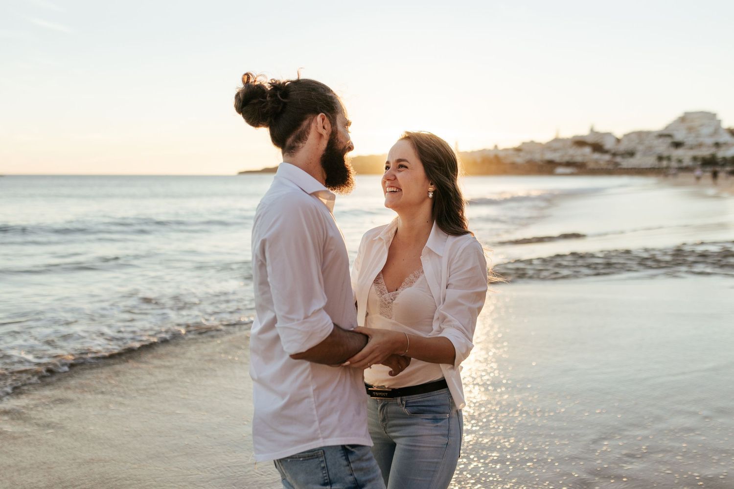 A couple sharing a romantic moment on the beach at sunset. Praia da Luz, Lagos, Algarve, Portugal.