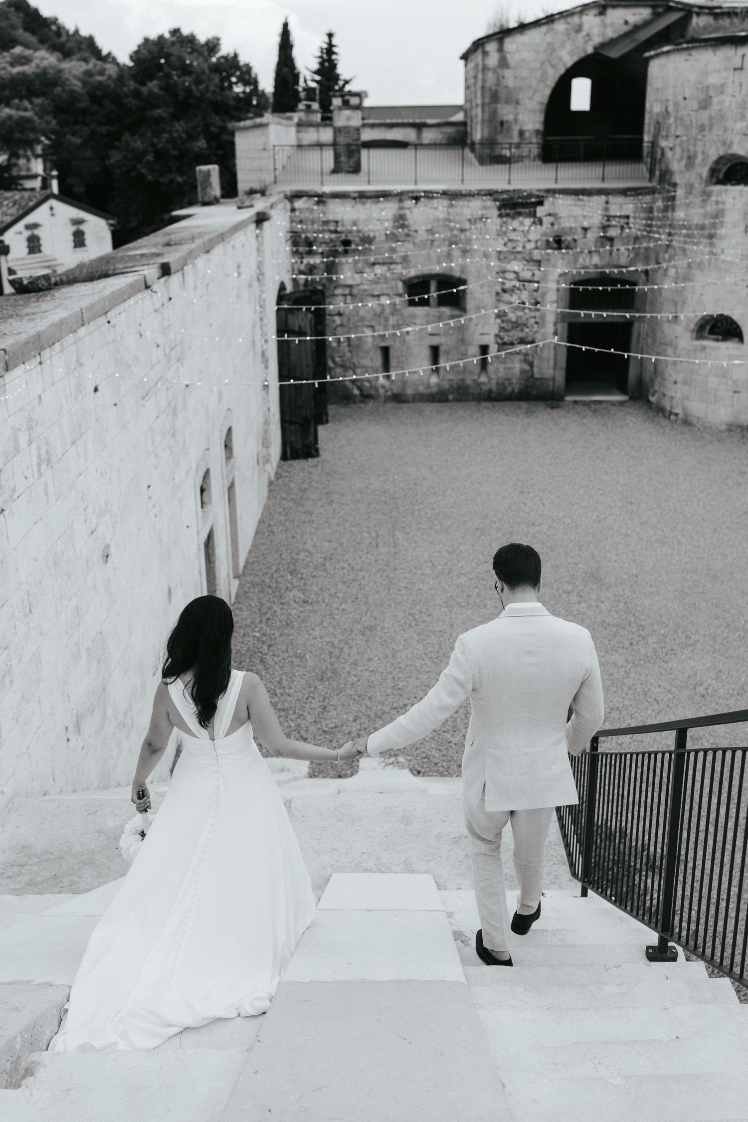 Couple holding hands while descending stone steps at historic venue.