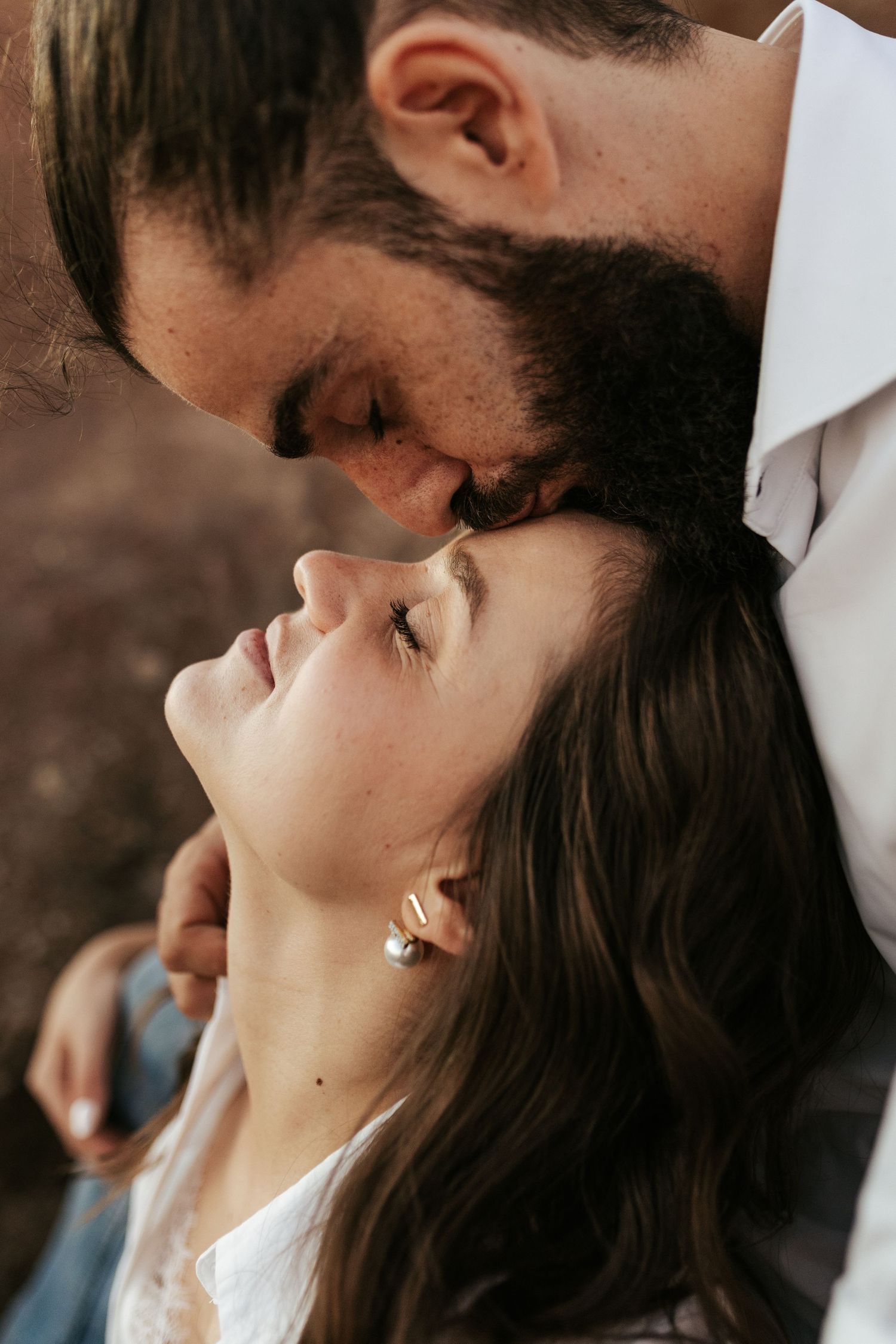 Close romantic profile shot shows couple in intimate moment with soft lighting and dreamy atmosphere.
