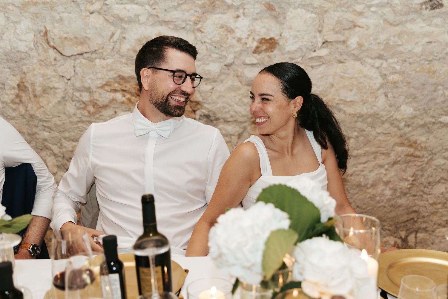 Wedding celebration in a rustic stone venue in Lago di Garda with white floral centerpieces and candlelight.