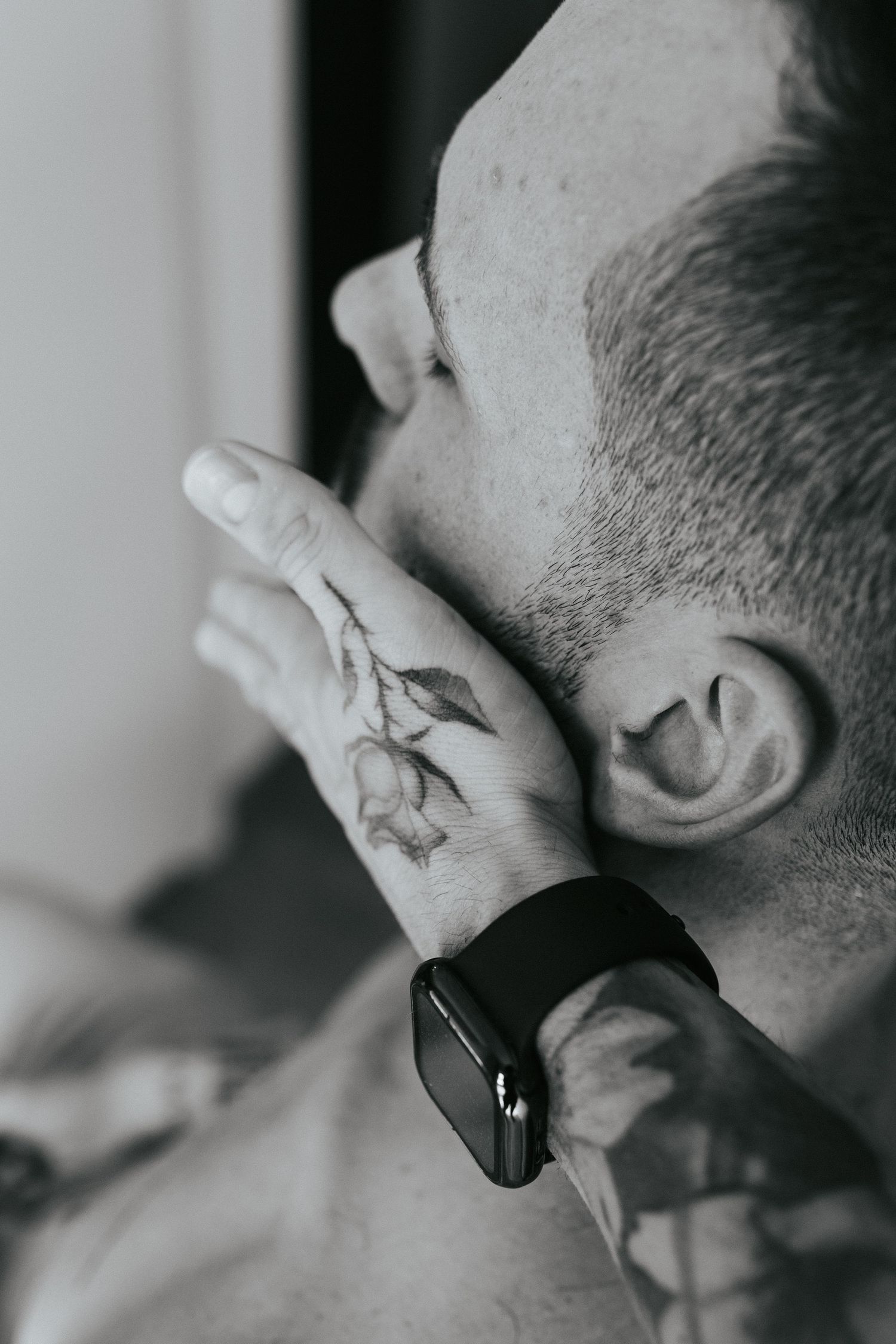 A close-up profile shot of someone putting on jewelry or touching their ear while wearing a smartwatch.