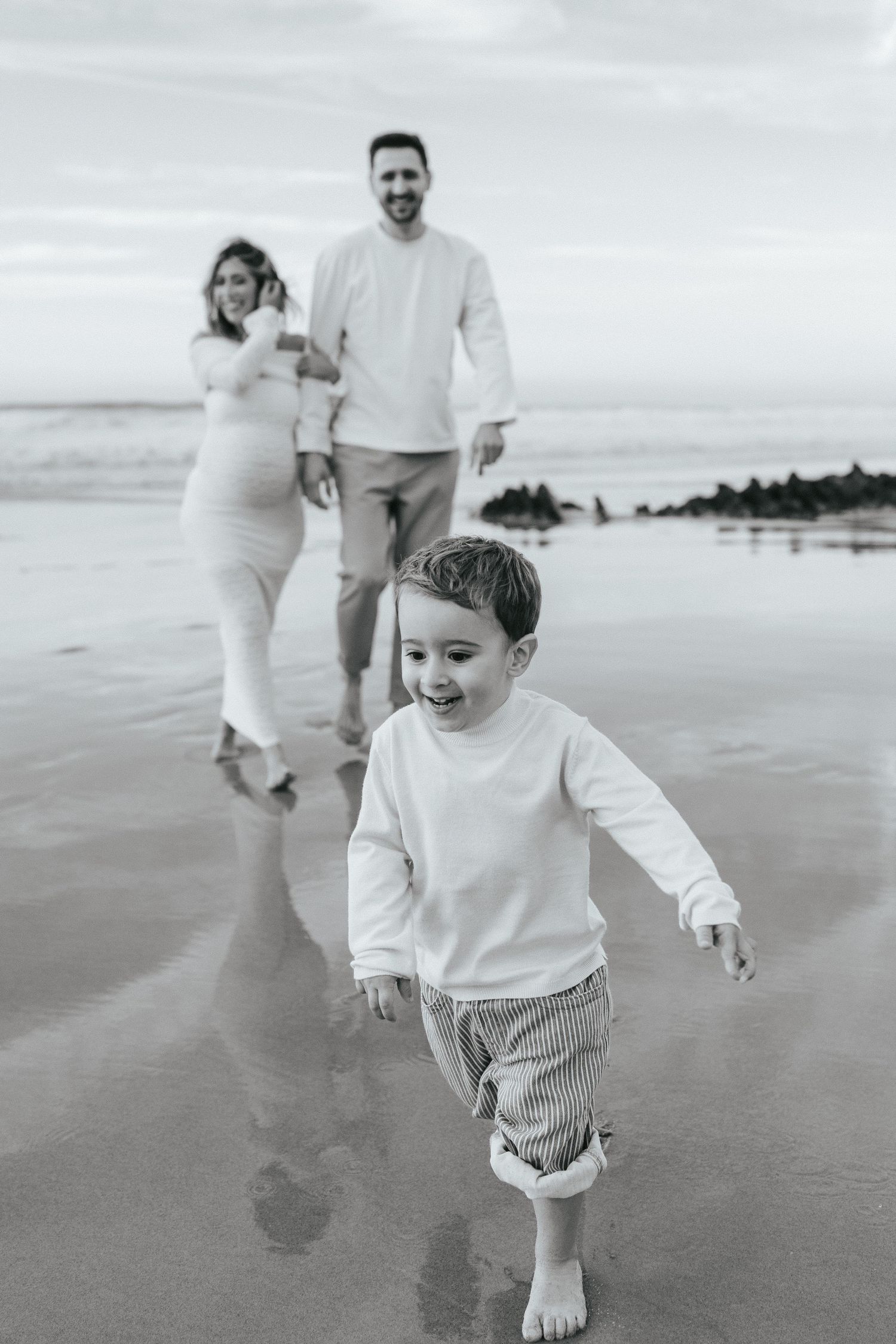 Black and white beach photos showing family moments with joyful running and playing along the shoreline. Praia da Cordoama, Sagres, Portugal