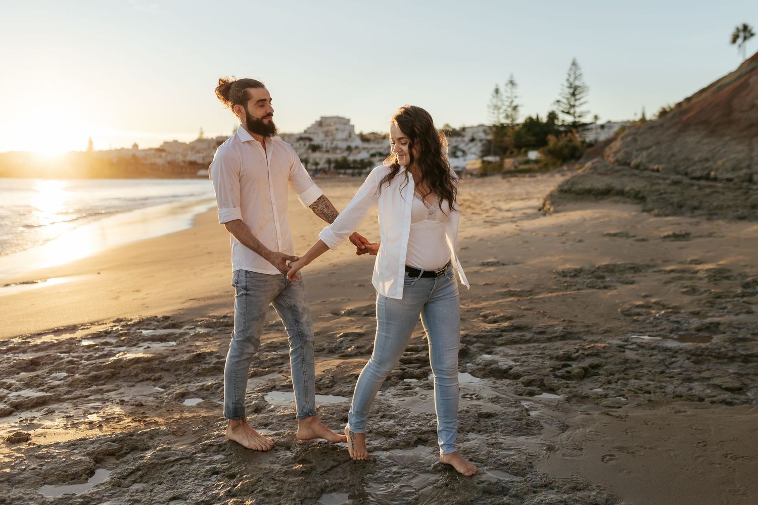 A couple taking a casual stroll along the shoreline during sunset. Praia da Luz, Lagos, Algarve, Portugal.