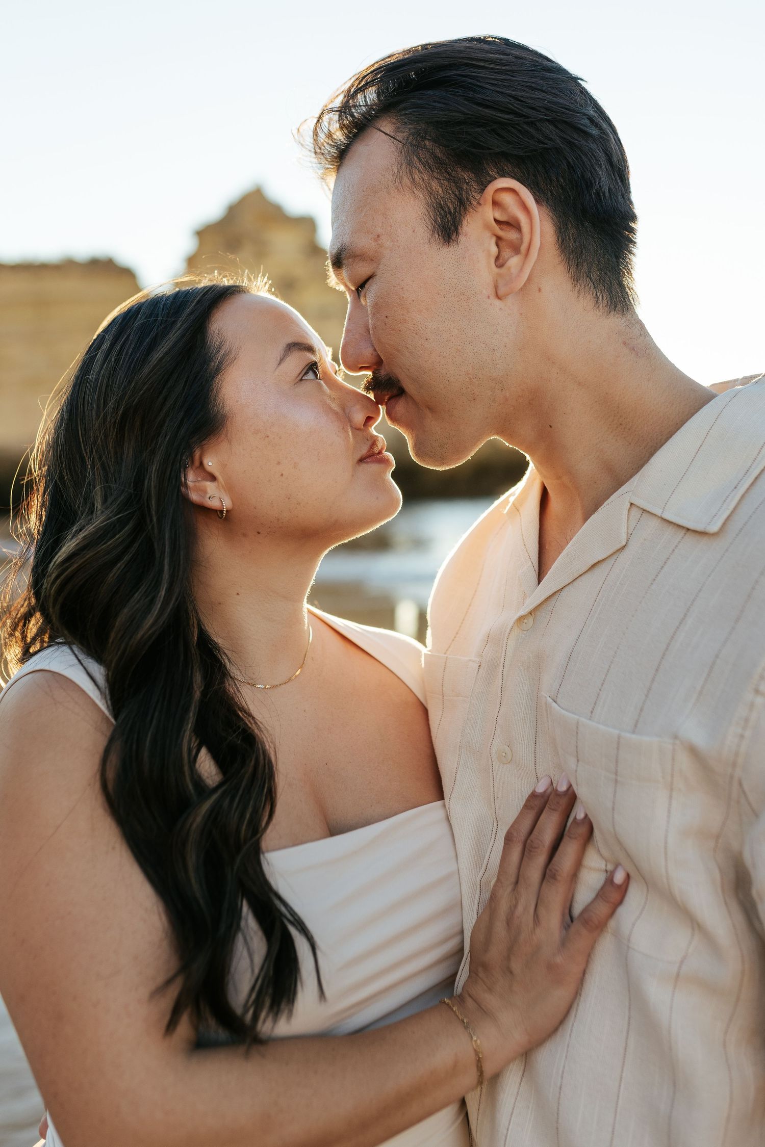 Romantic couple sharing an intimate embrace during golden hour sunset with warm backlighting.